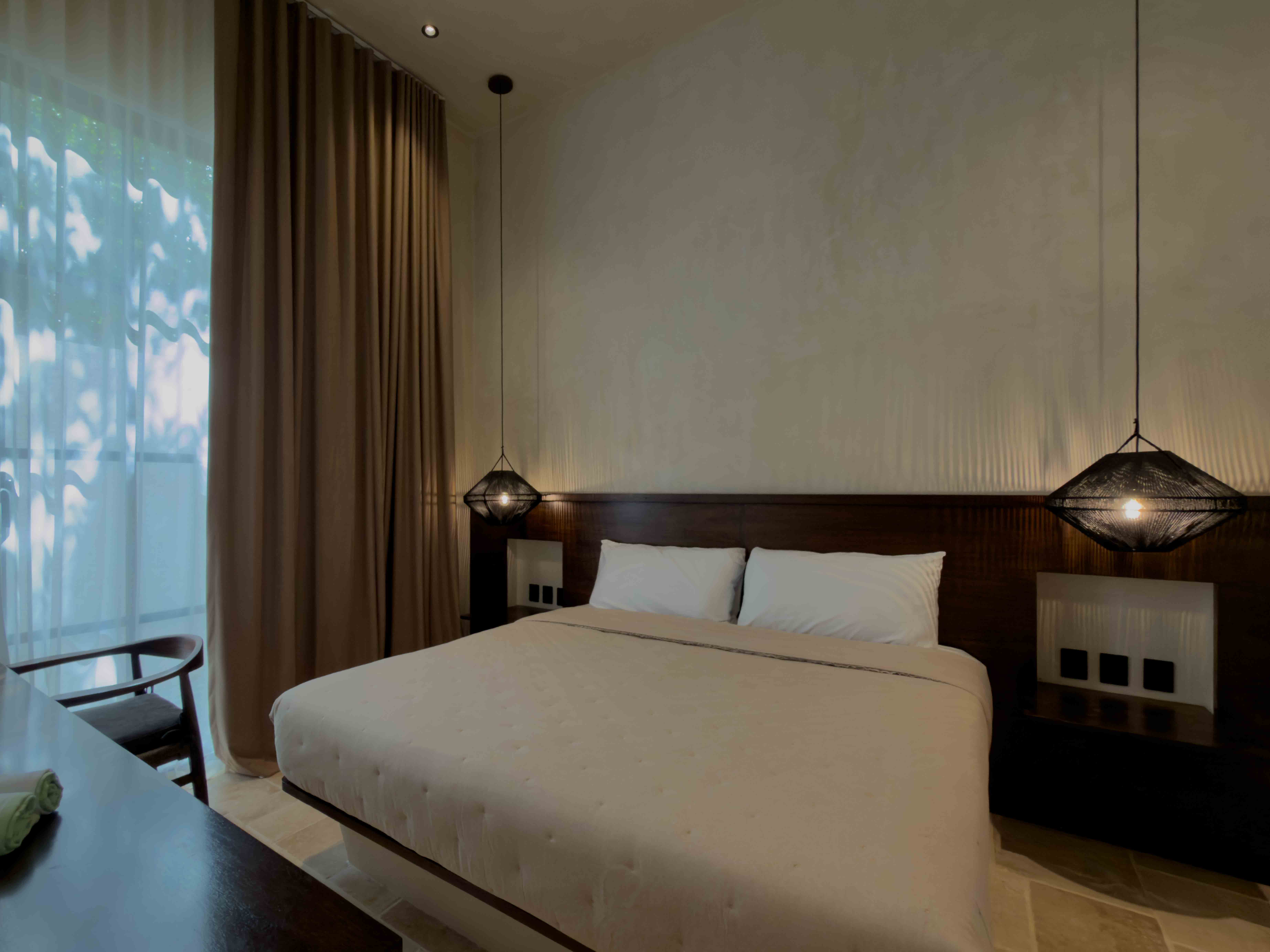 Minimalist king suite with dark wood headboard and pendant lighting