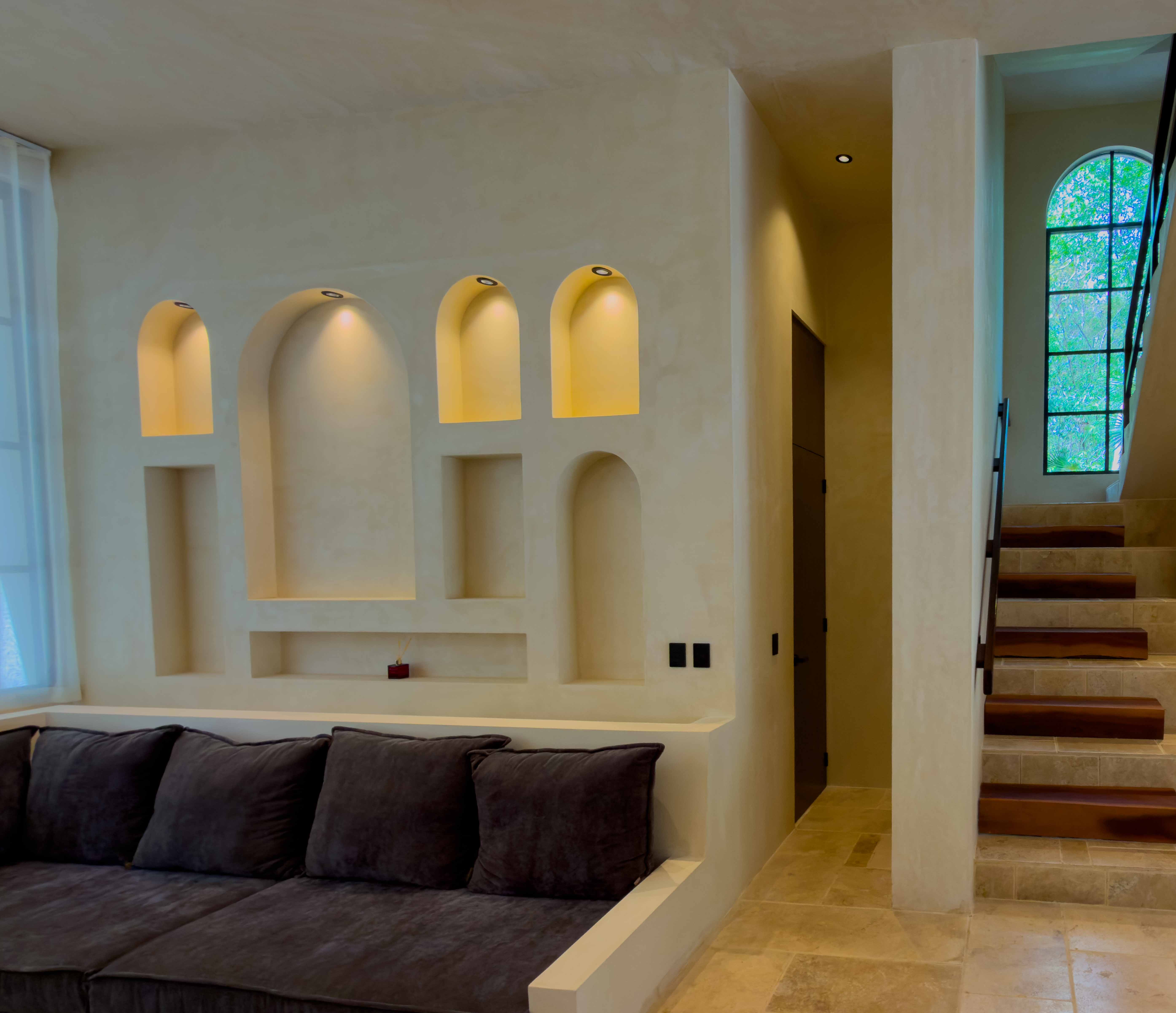 Minimalist indoor lounge featuring arched wall niches and integrated stone staircase.
