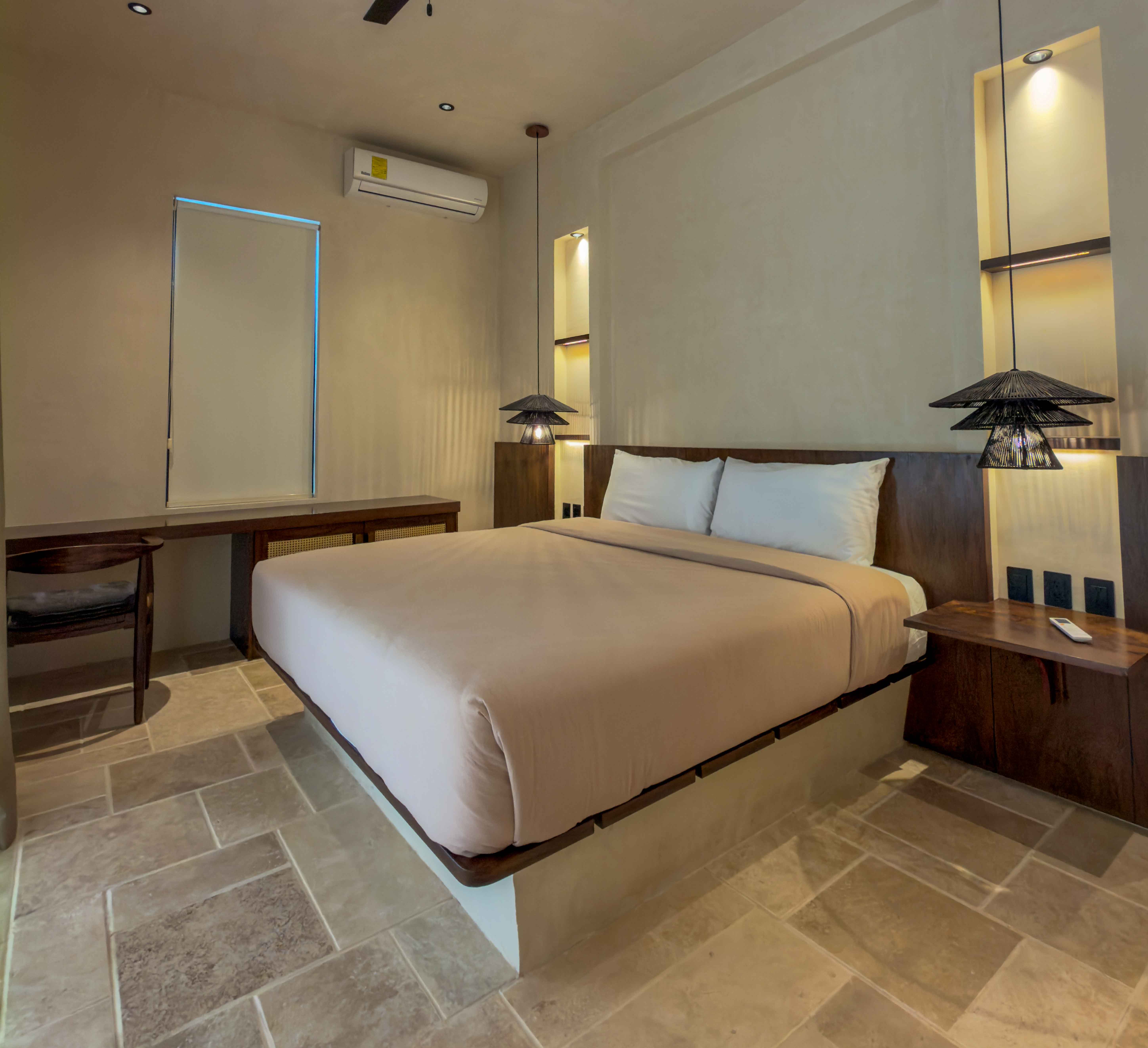 Minimalist luxury bedroom with integrated wood headboard, stone tile floors, and custom lighting fixtures.