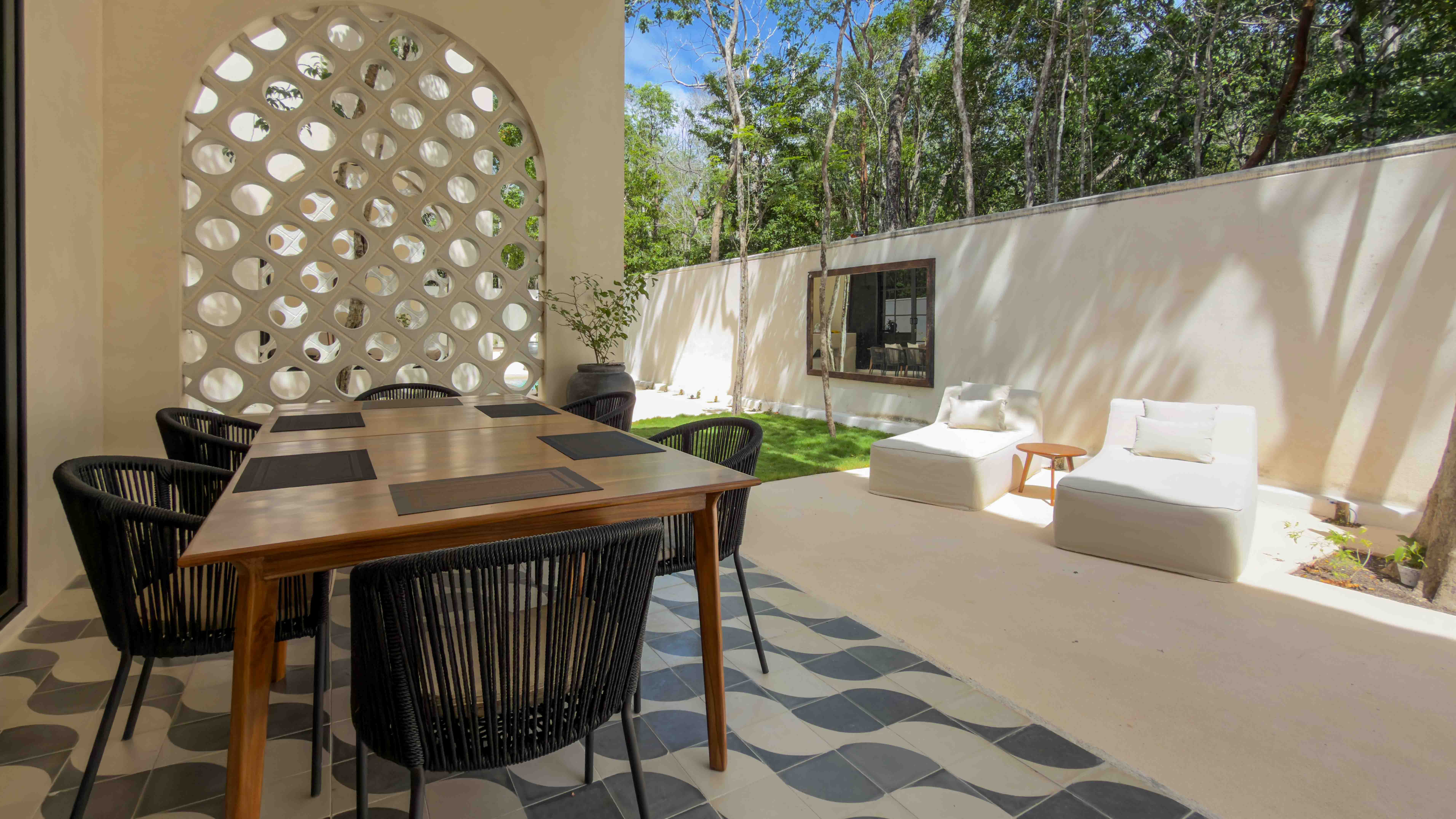Outdoor dining and lounge area on a covered patio with designer tile and arch detail.
