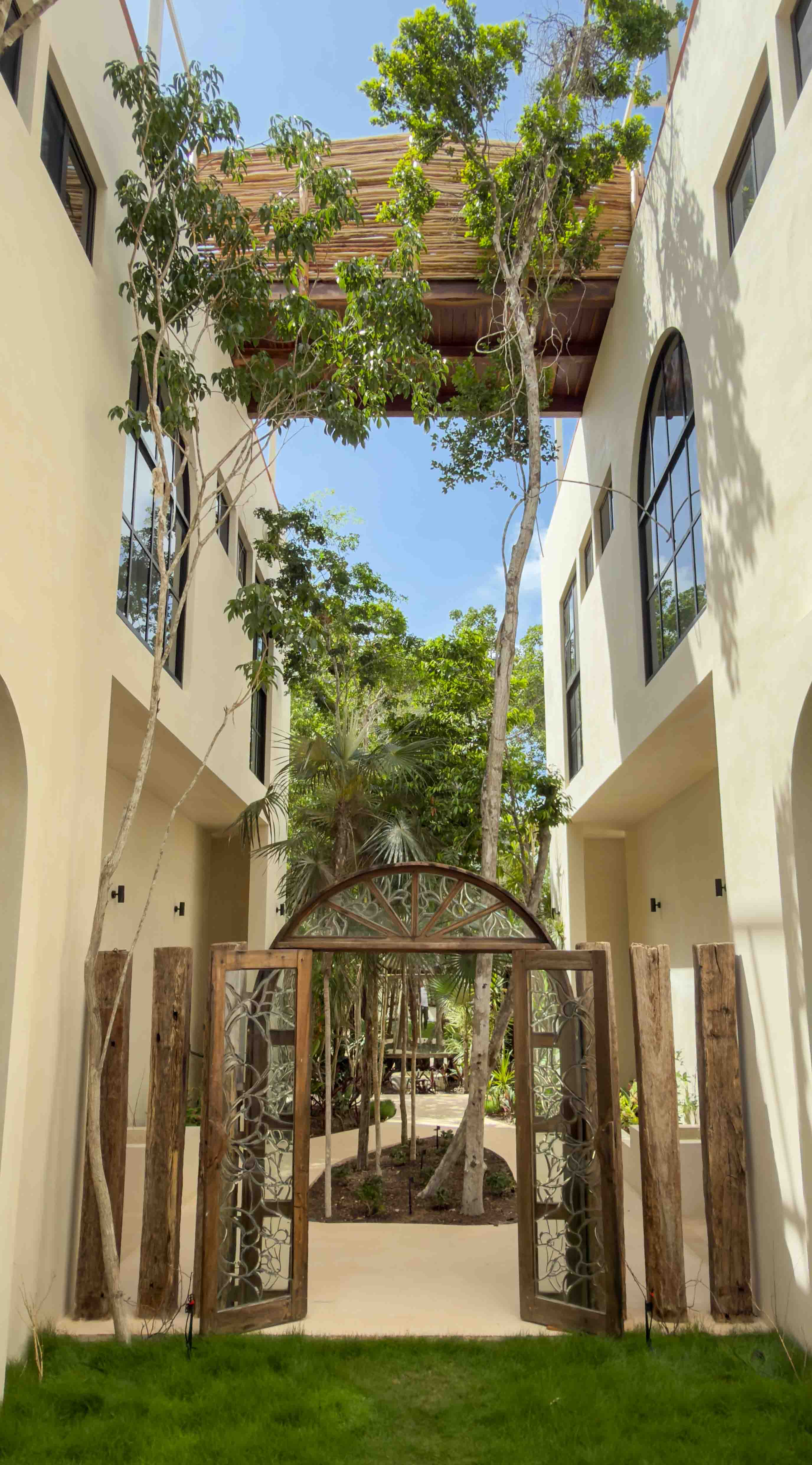 Architectural view of the ornate garden gates and high-walled courtyard with lush trees.