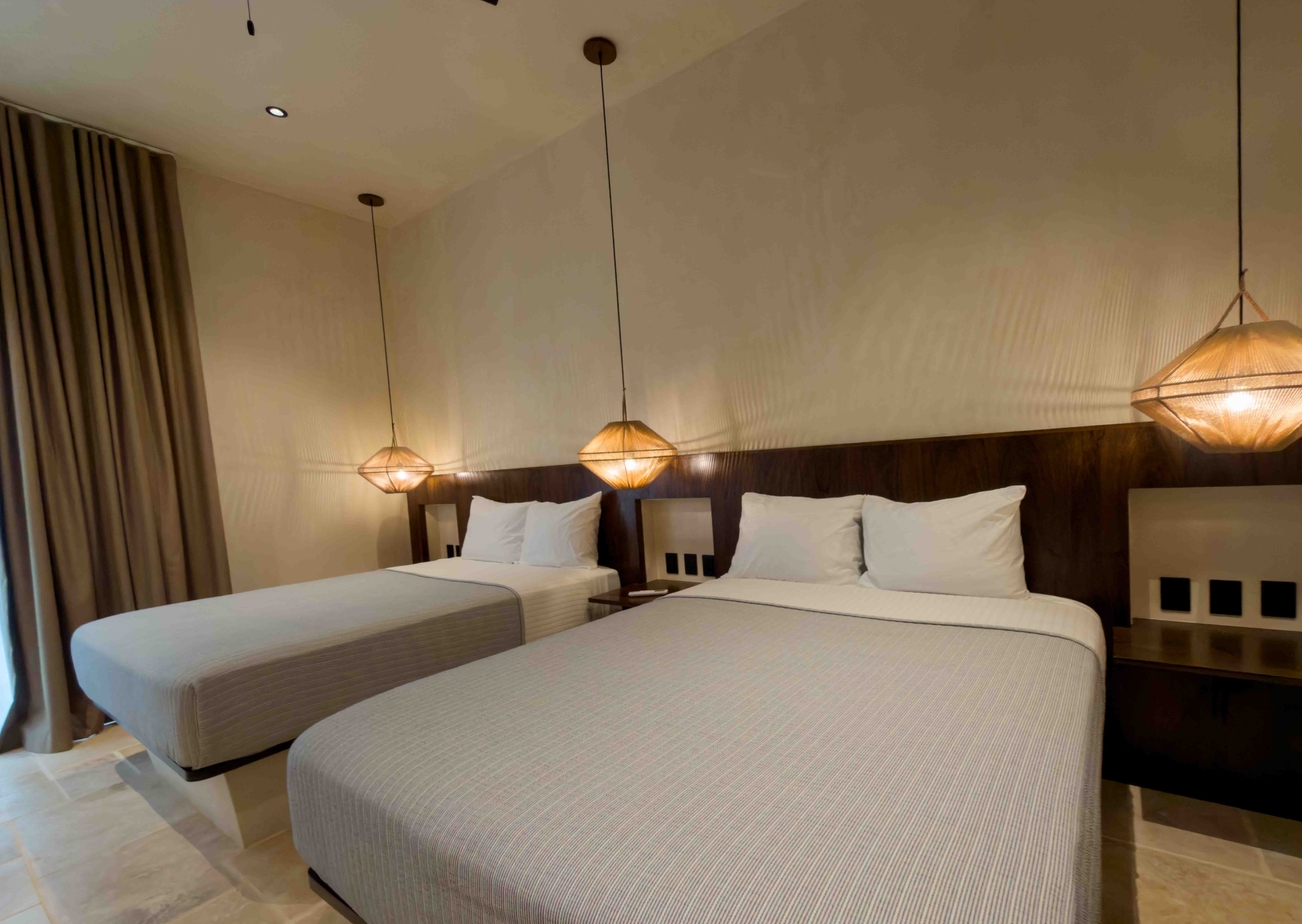 Twin bed setup with dark wood headboards and warm pendant lighting.