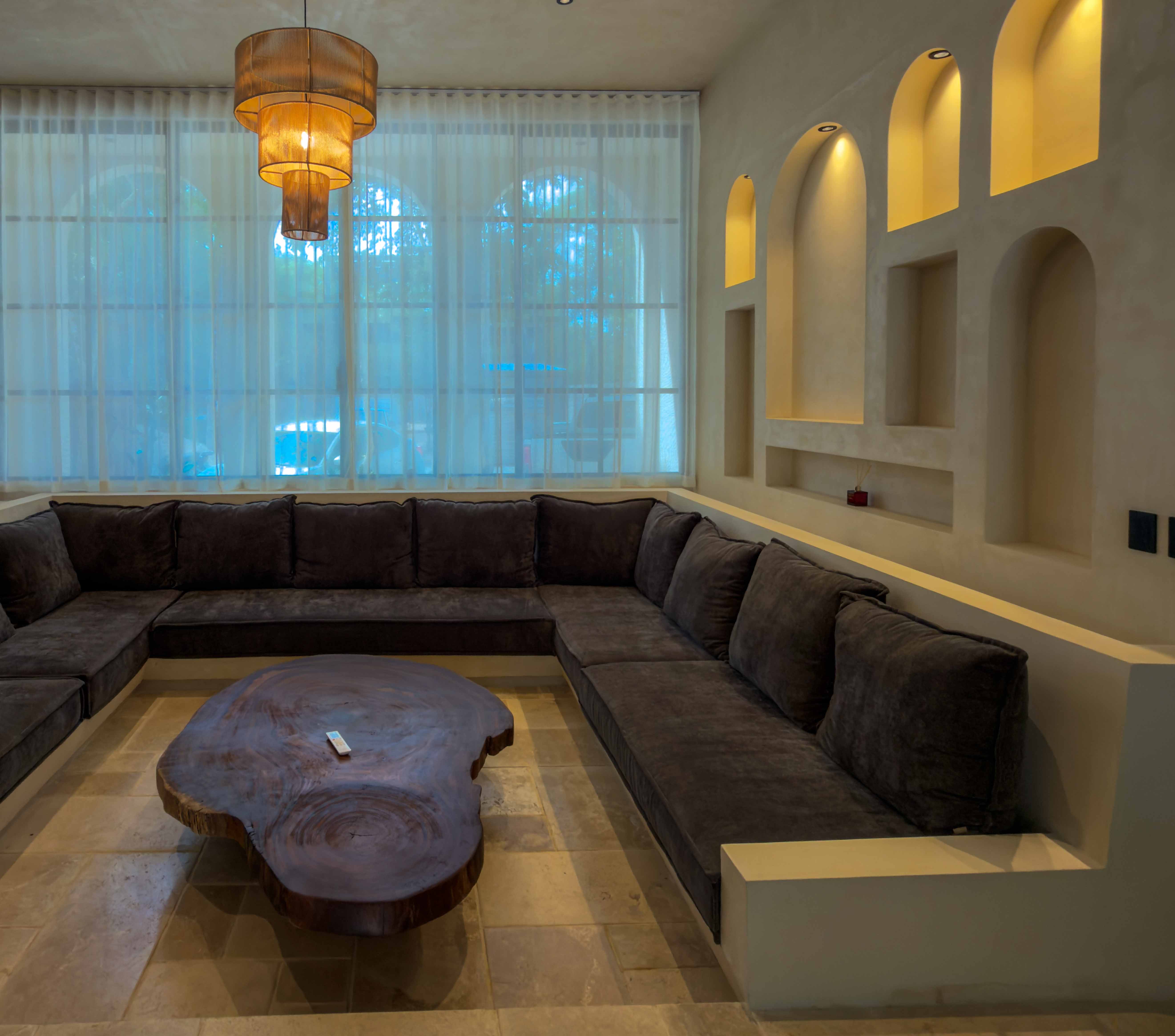 Indoor sunken lounge with a custom live-edge wooden table and arched lit wall niches