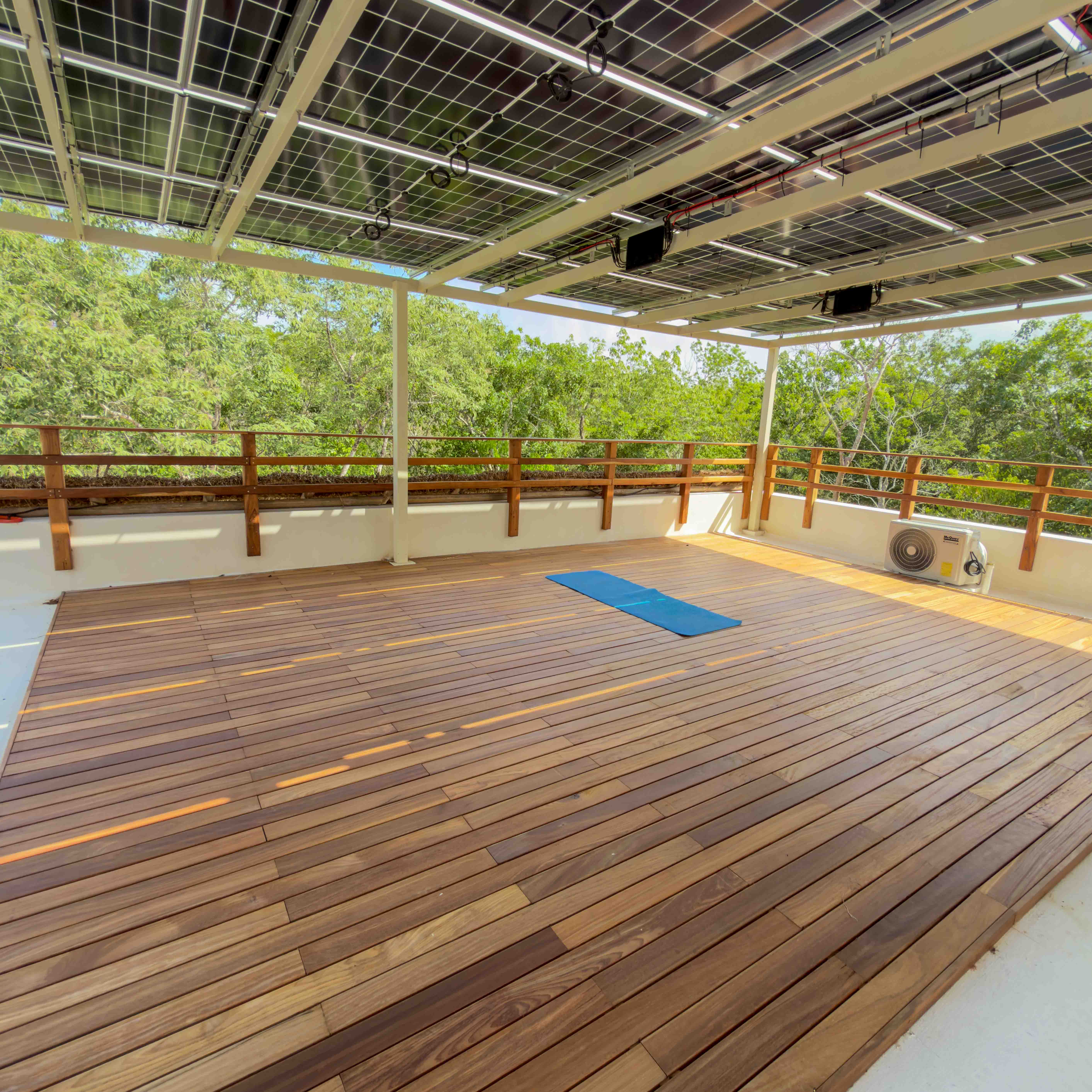 Spacious rooftop yoga deck with solar panel canopy and jungle views.