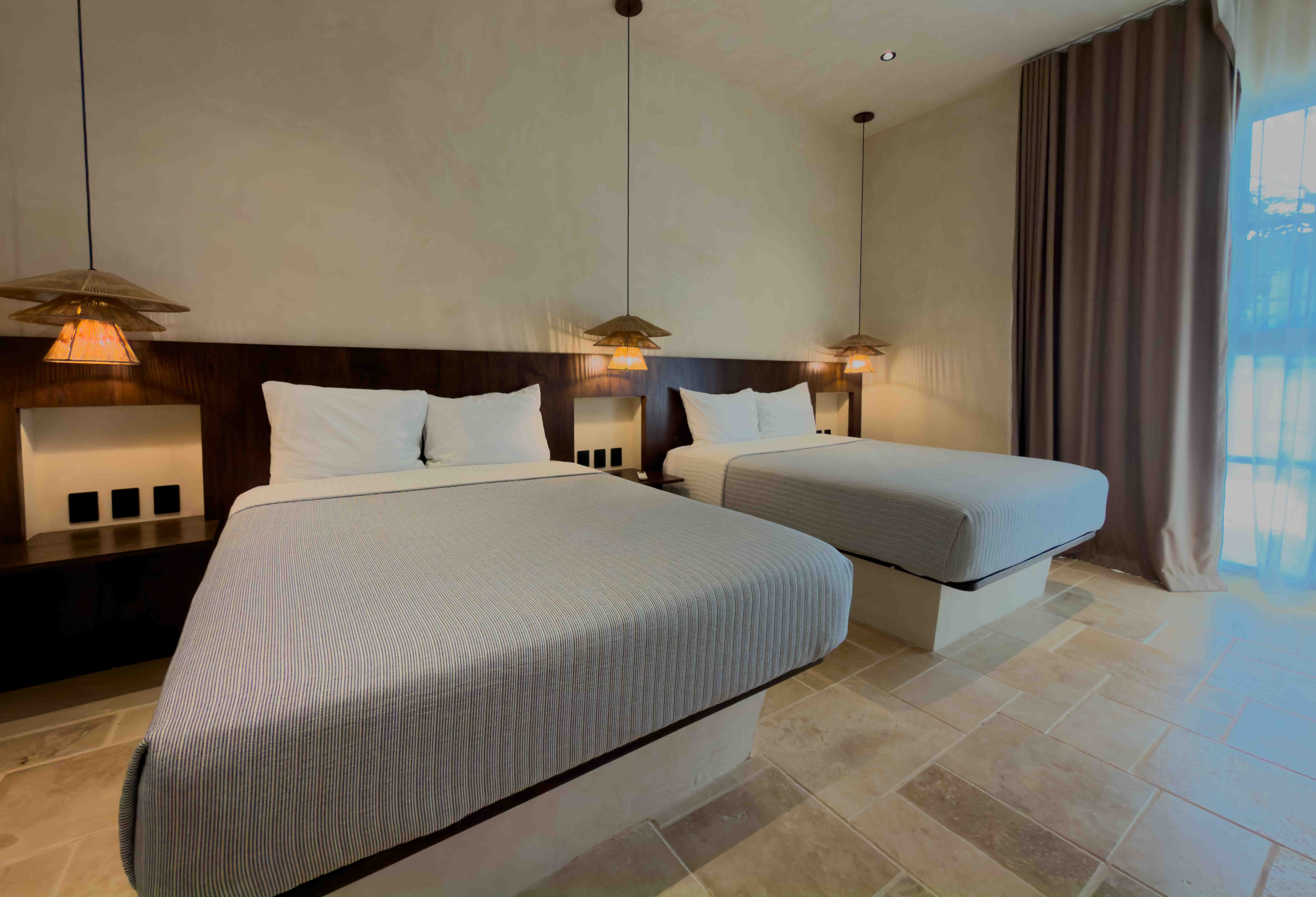 Two-queen suite with wooden headboards and hanging pendant lights