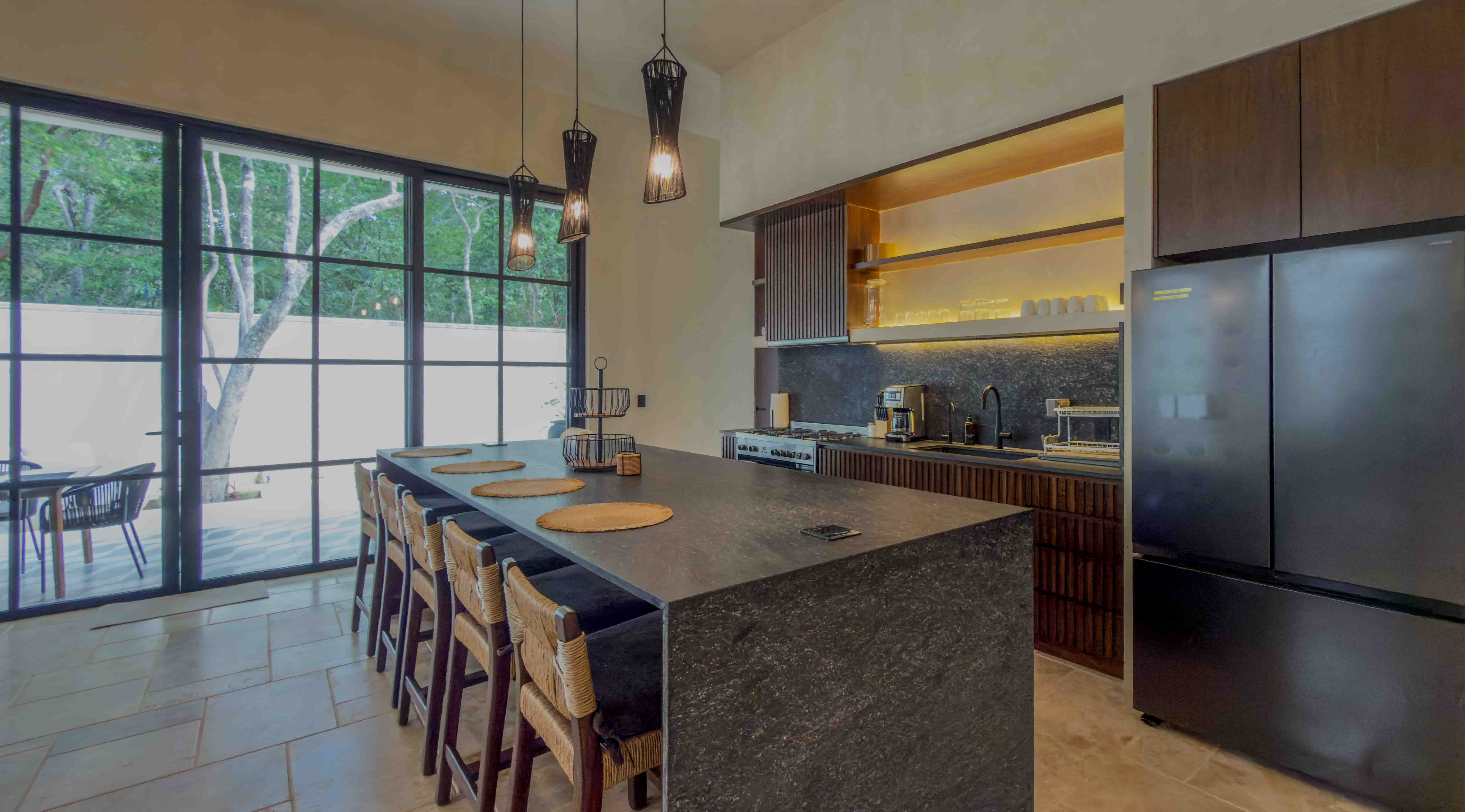 Modern designer kitchen with waterfall island and large glass doors to garden.