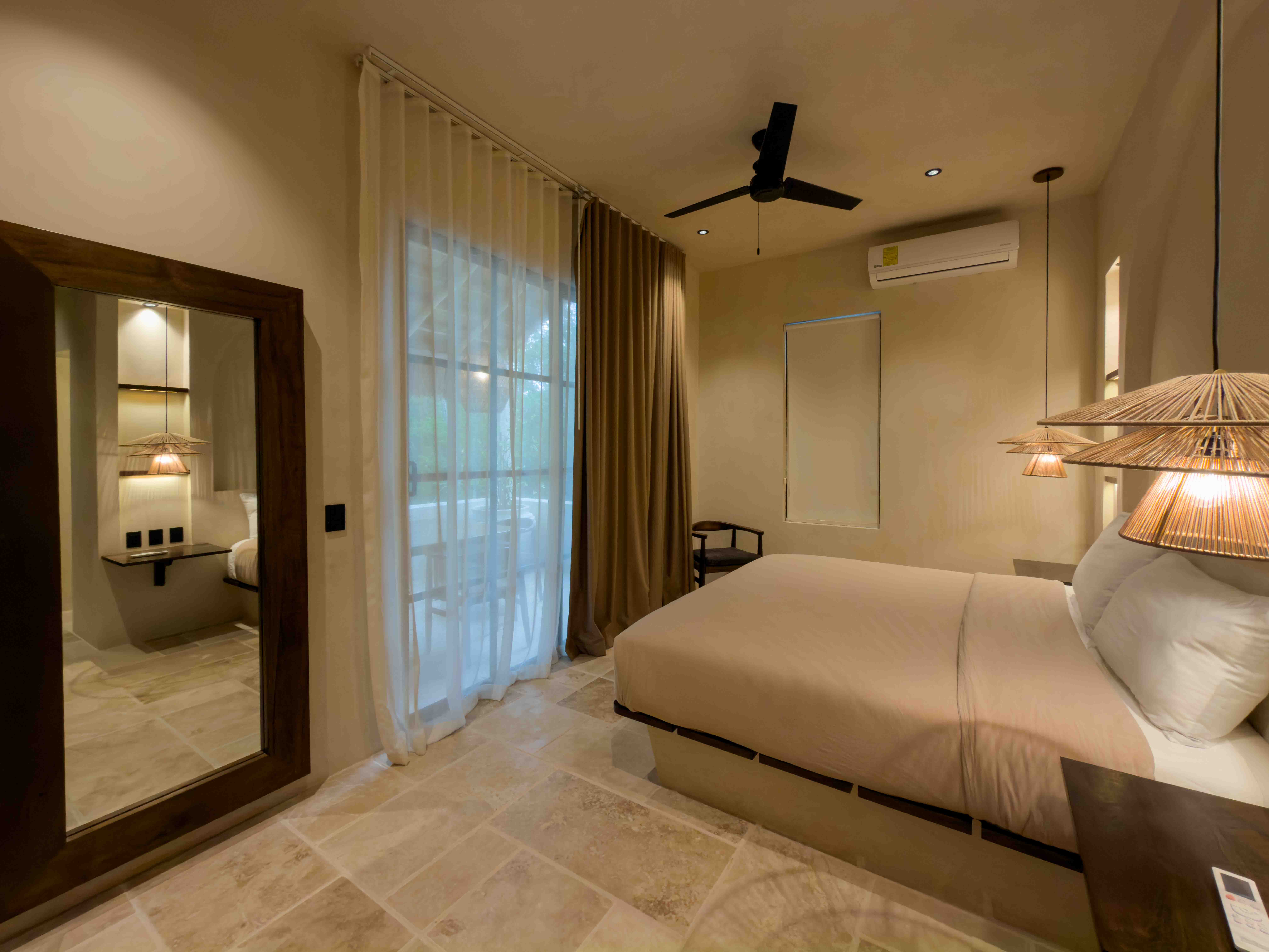 Spacious king suite with wood-framed mirror and floor-to-ceiling drapes