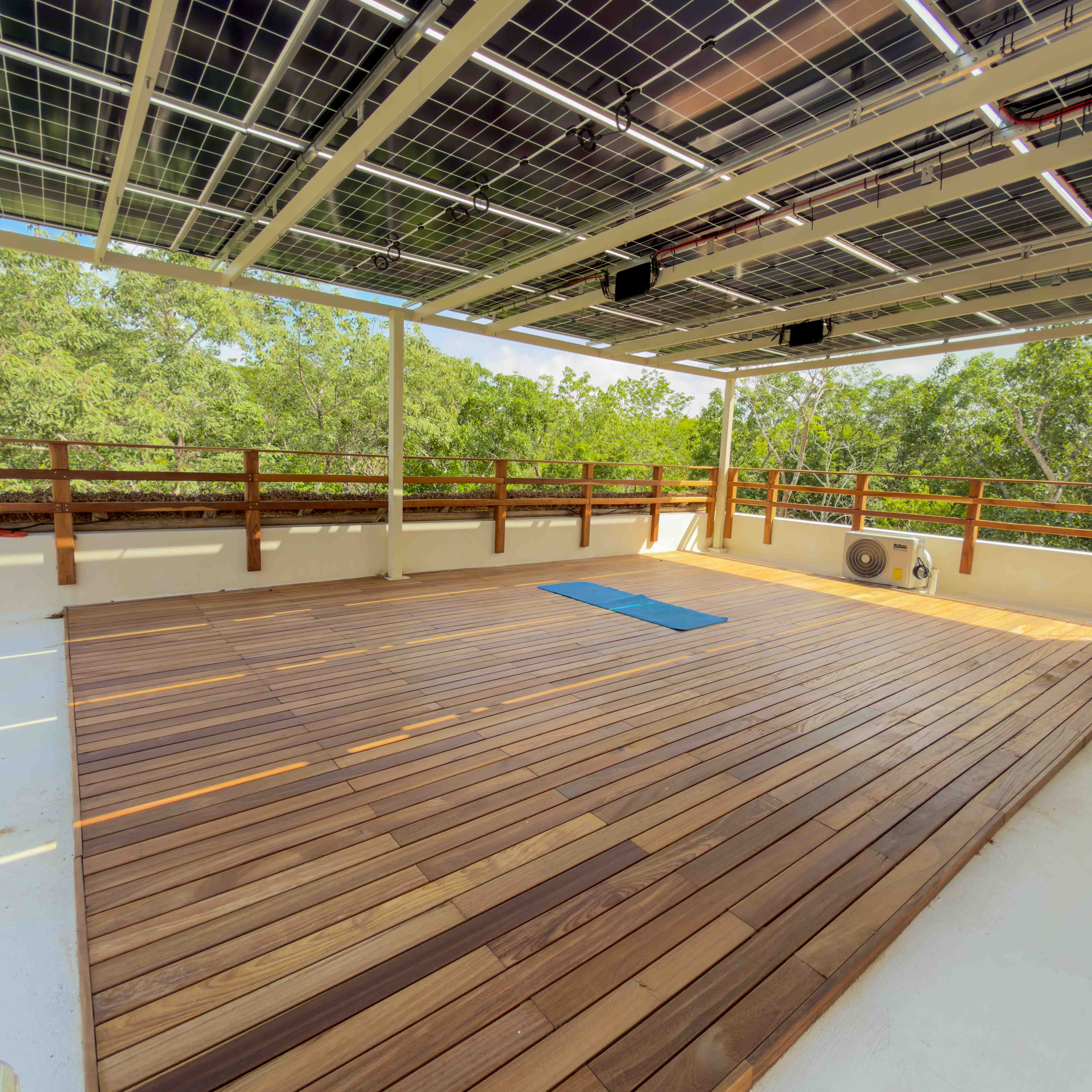 Wooden rooftop yoga deck with solar panel canopy and jungle views.