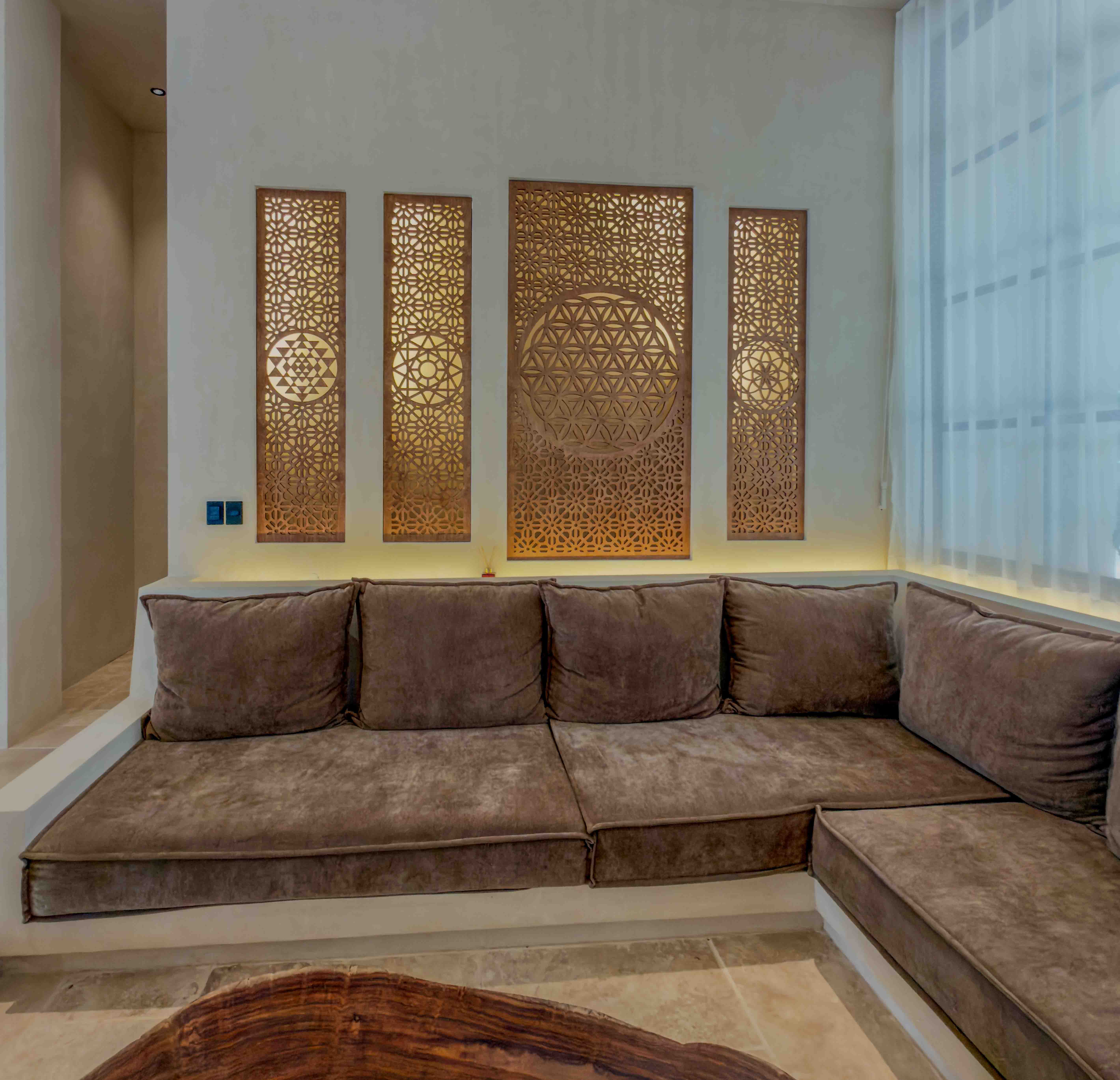Indoor lounge area featuring built-in sofa and intricate geometric wall art panels.