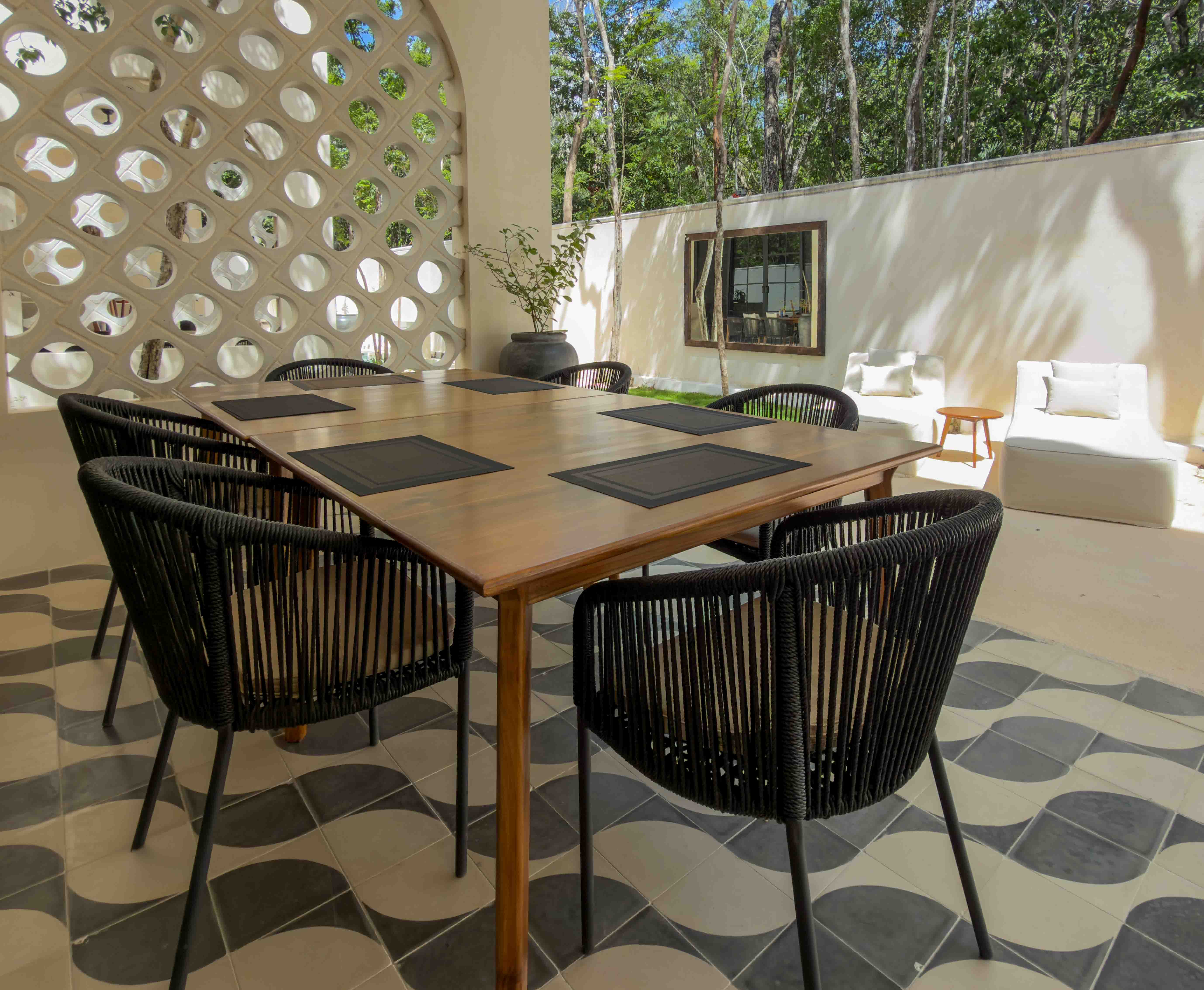 Outdoor dining area with pattern tile under covered terrace and courtyard view.