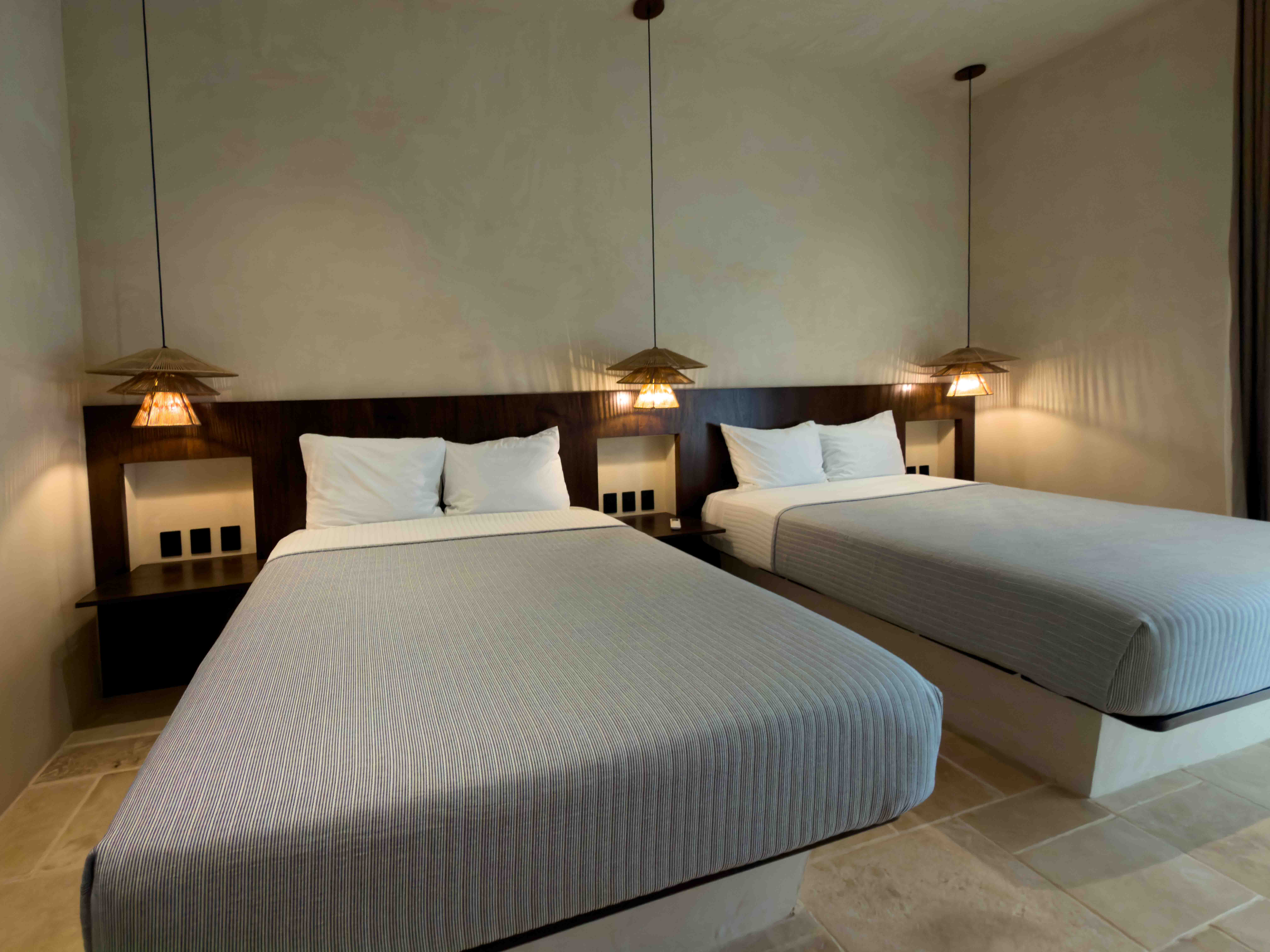 Minimalist double bedroom with custom dark wood headboard and warm pendant lighting.