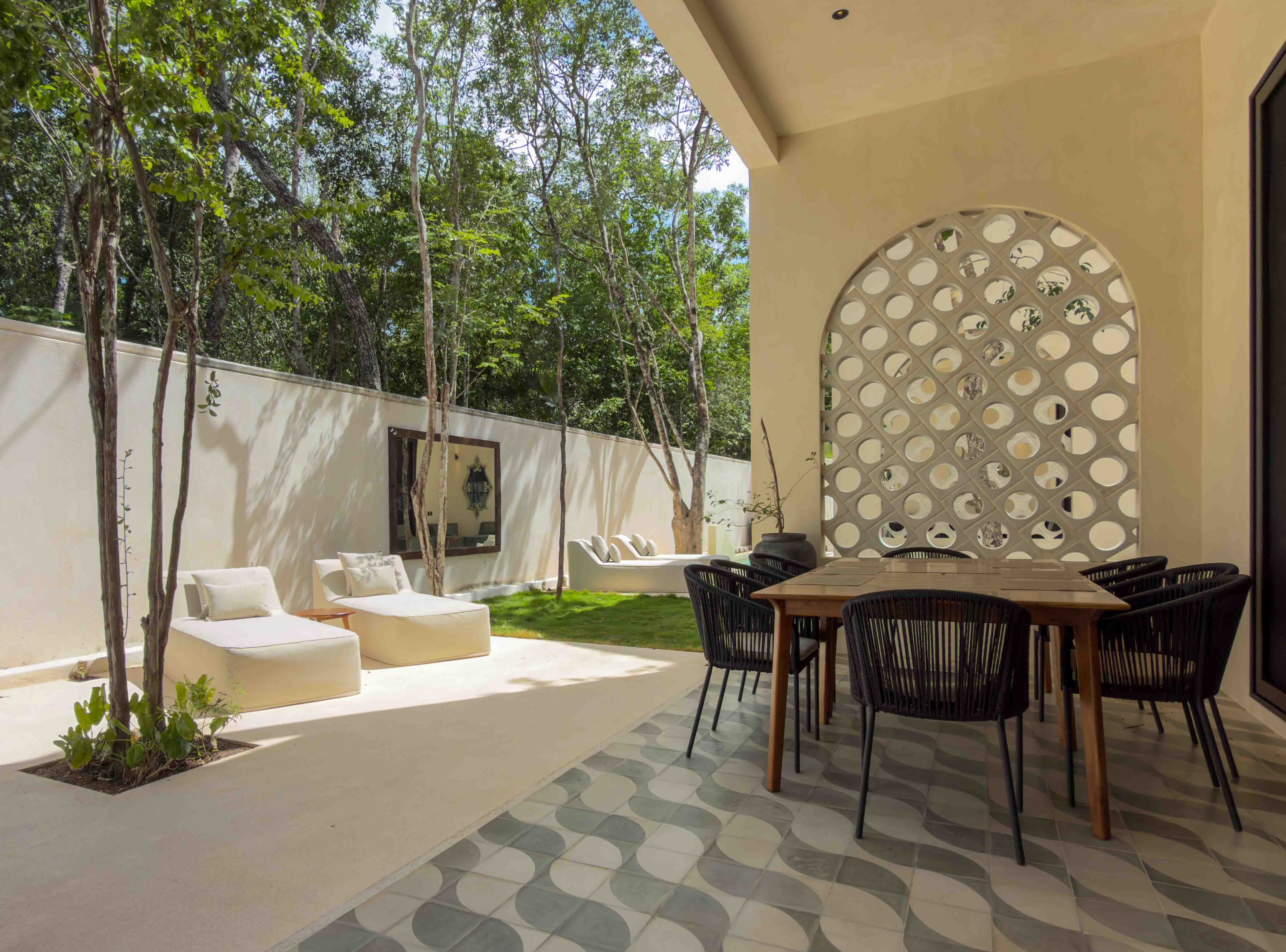 Covered outdoor dining area with wave-patterned tiles and lounge seating overlooking the garden.