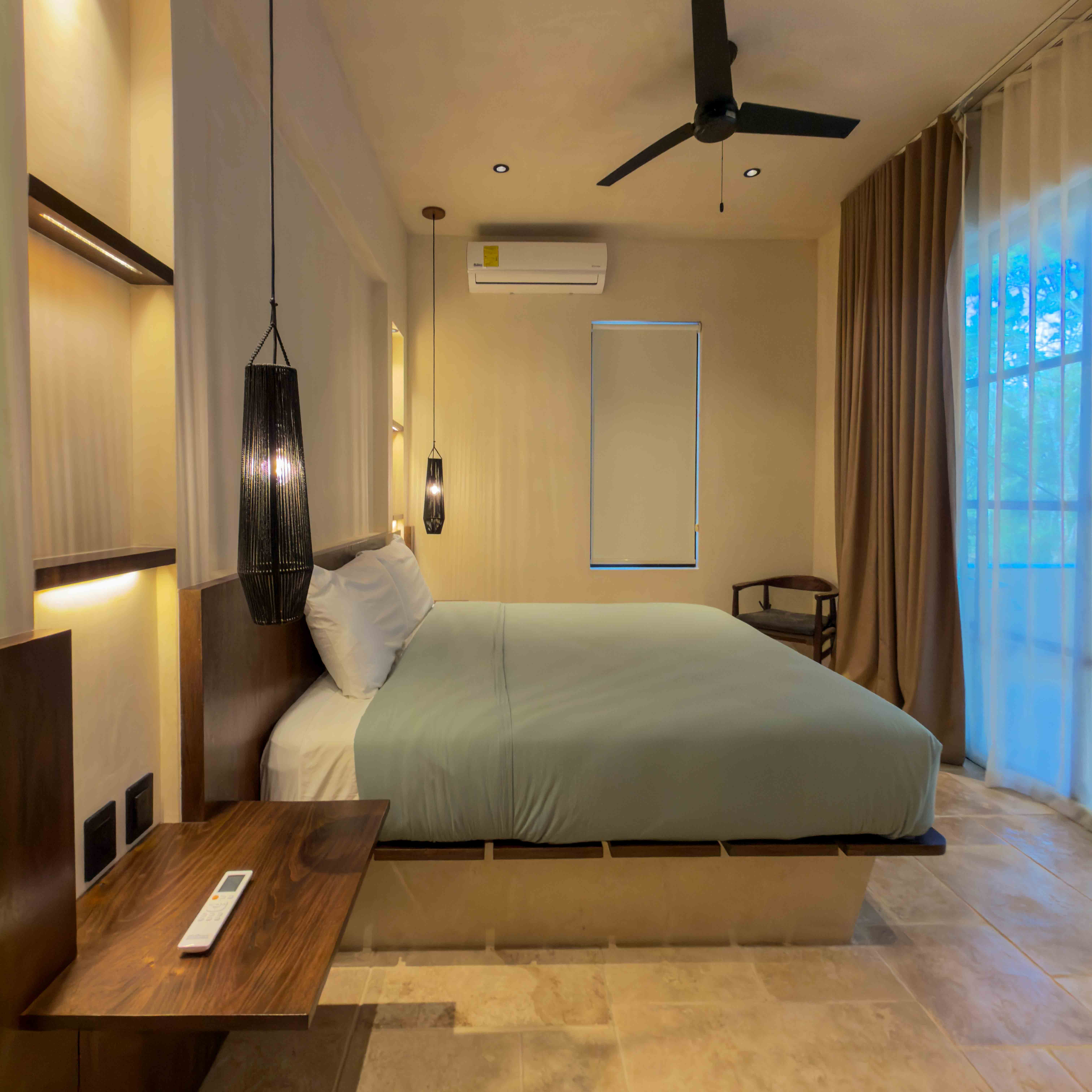 Modern minimalist bedroom with warm pendant lighting and stone flooring.