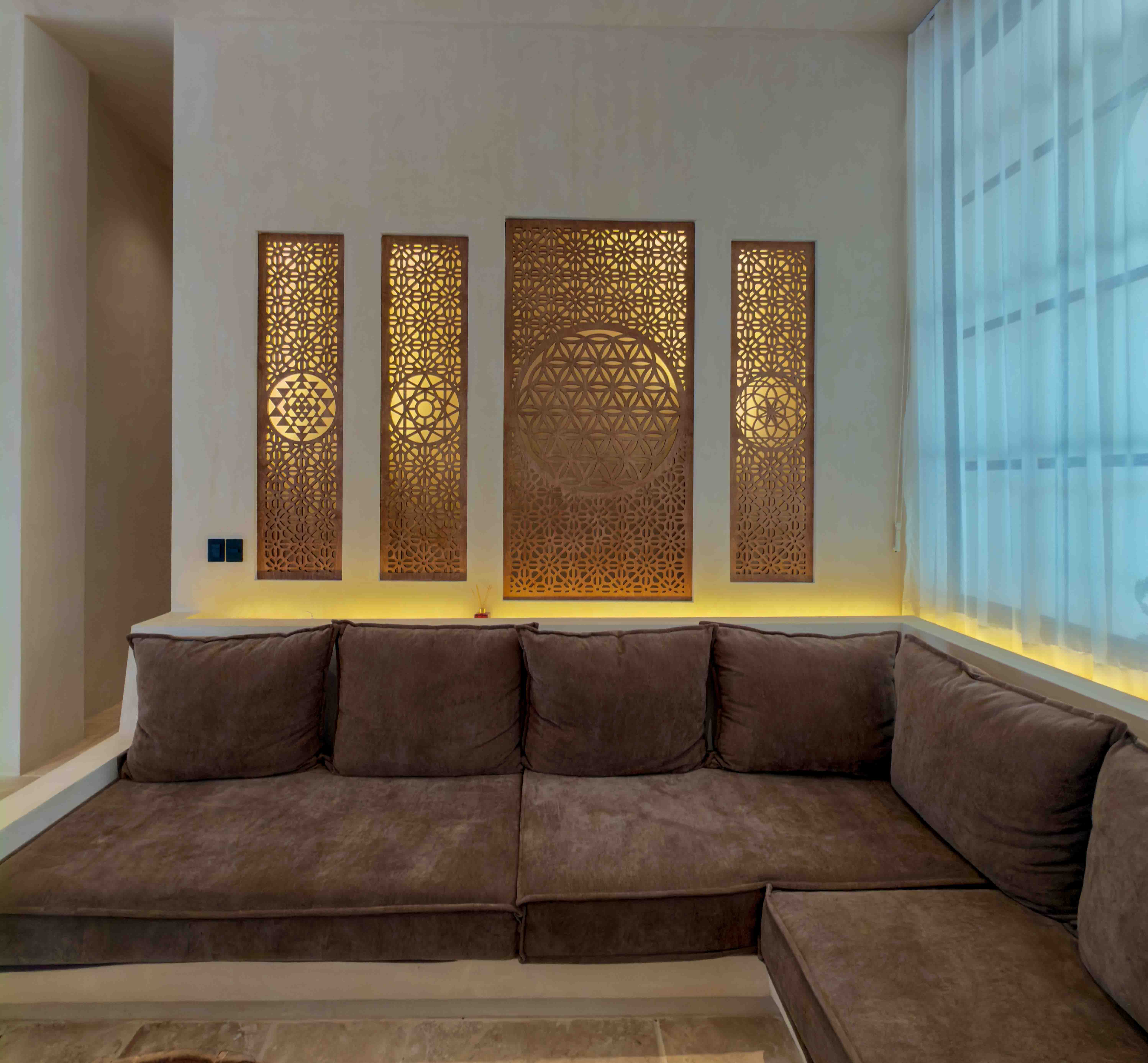 Built-in lounge seating featuring backlit filigree wall art panels with geometric motifs.