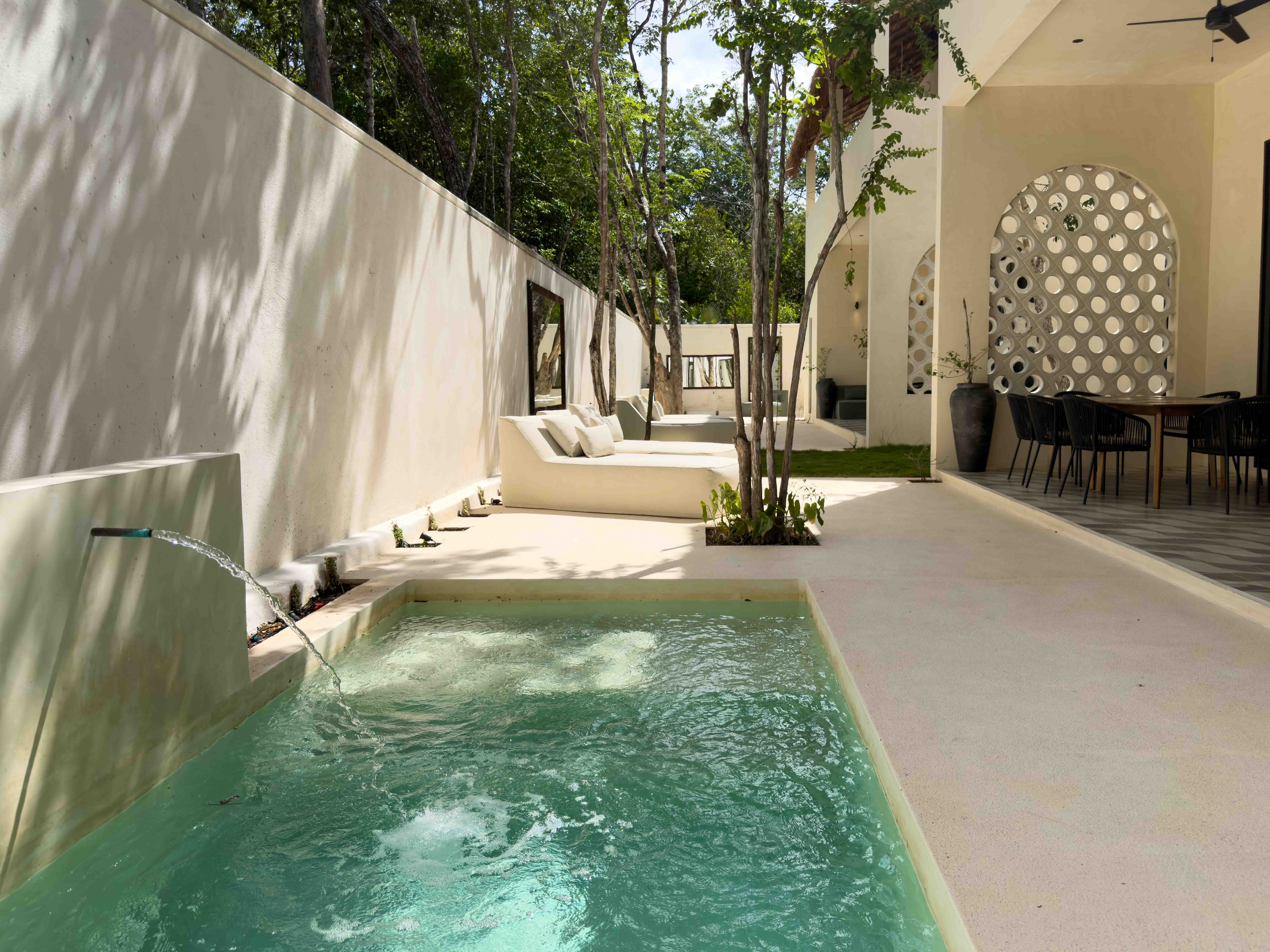 Small garden plunge pool with water feature and lounge area.