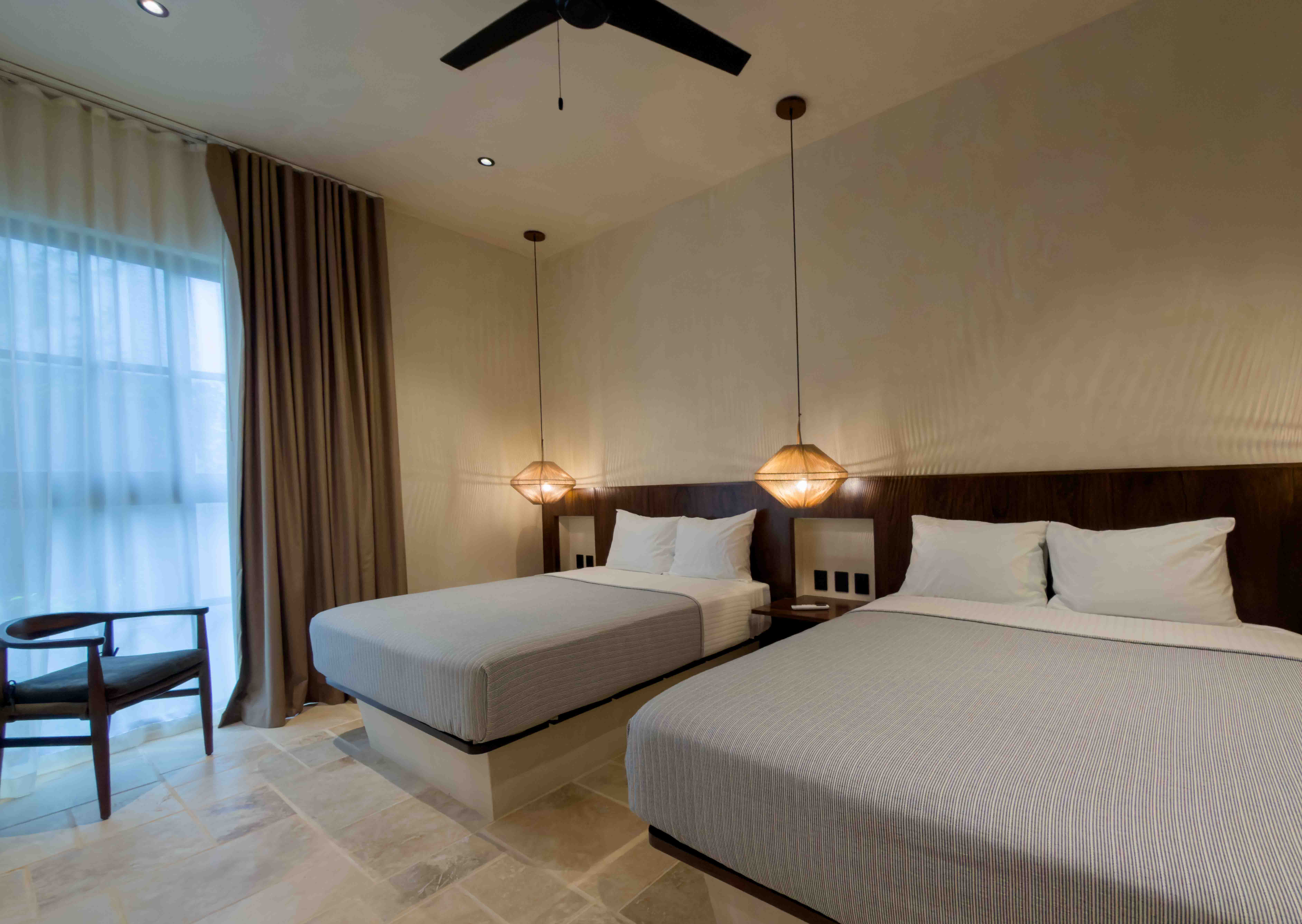Minimalist double bedroom with glowing pendant lights and warm timber accents.
