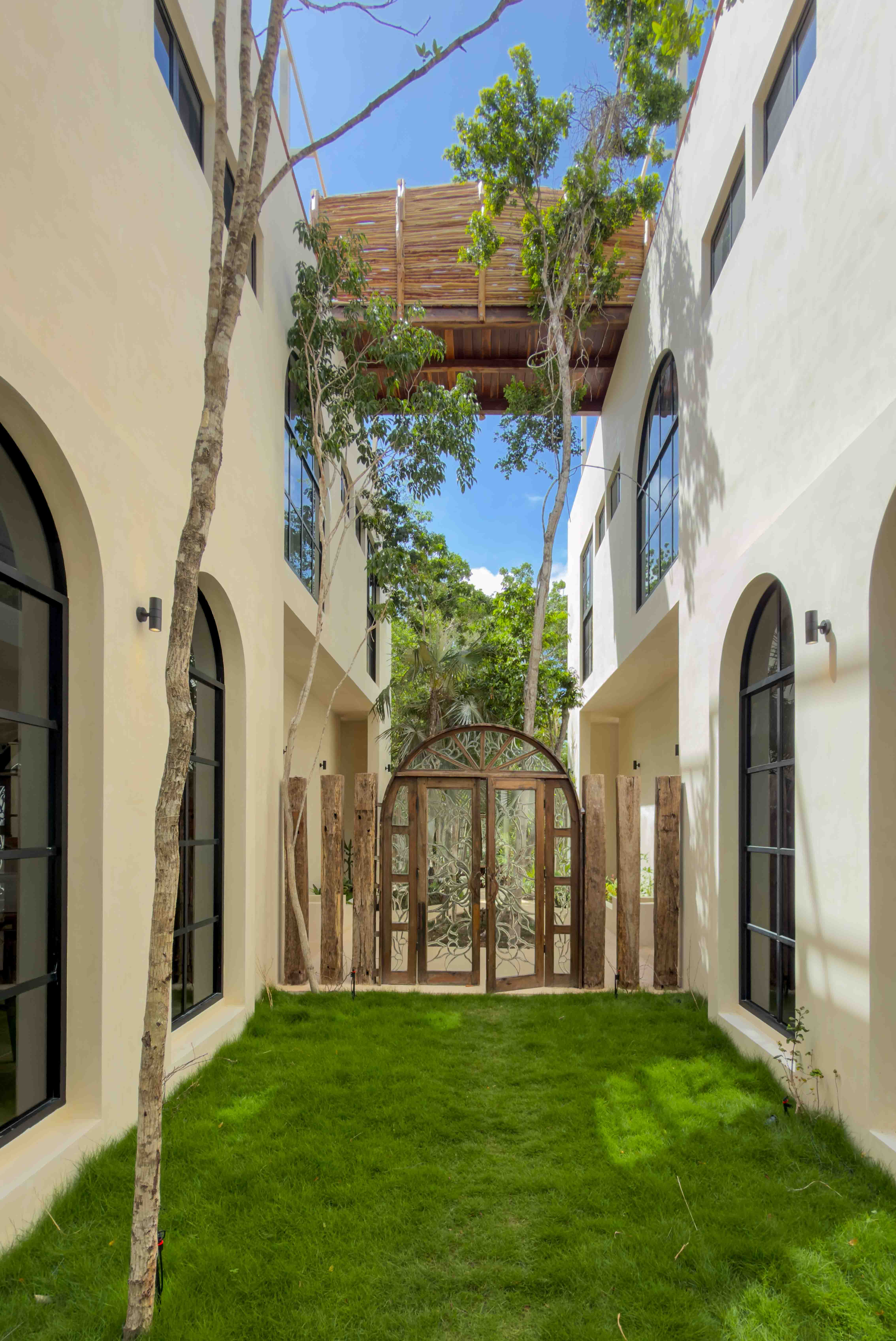 Grass courtyard between the two villas with the rooftop bridge above