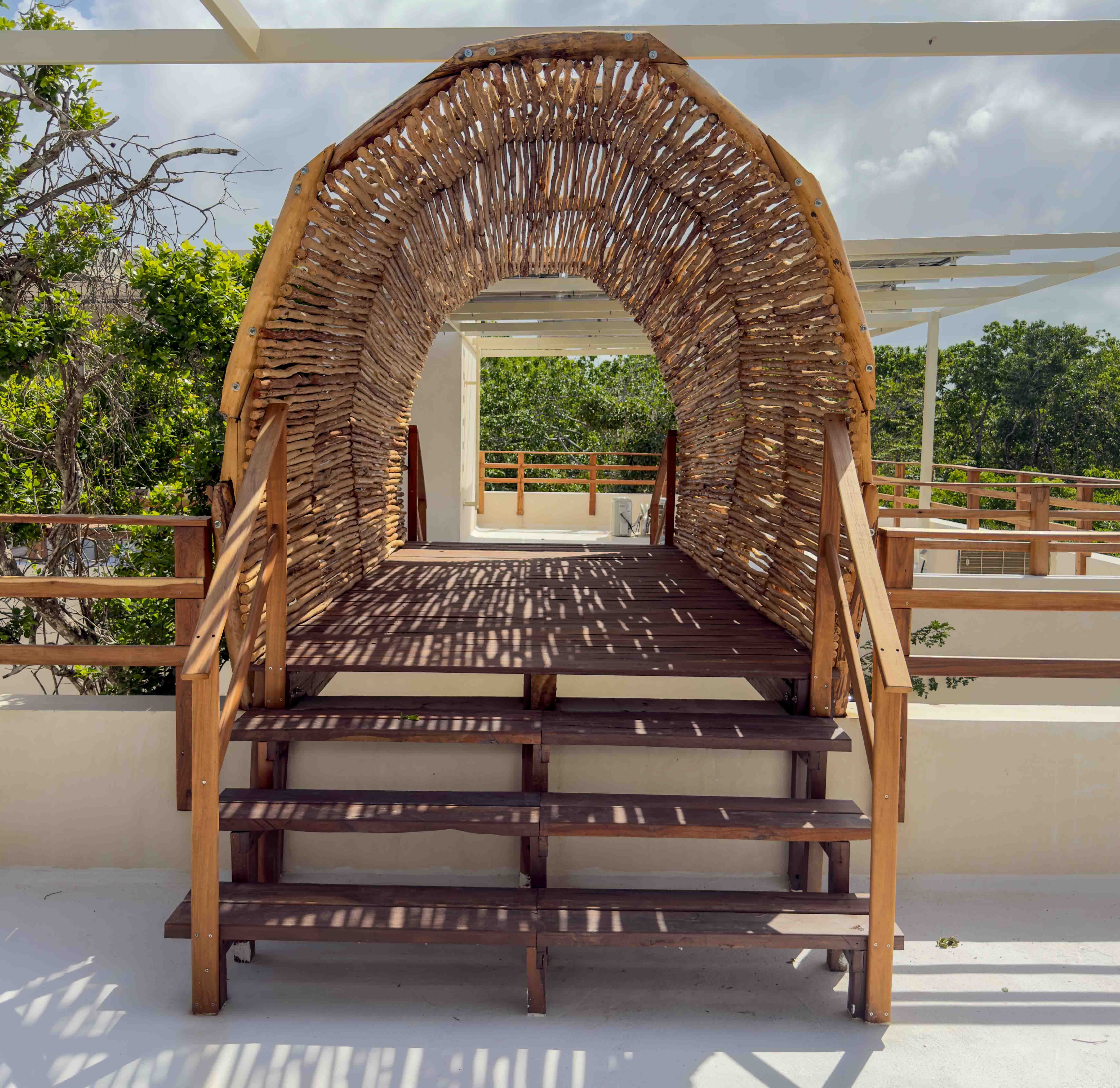 Wooden archway bridge on the rooftop terrace surrounded by tree views