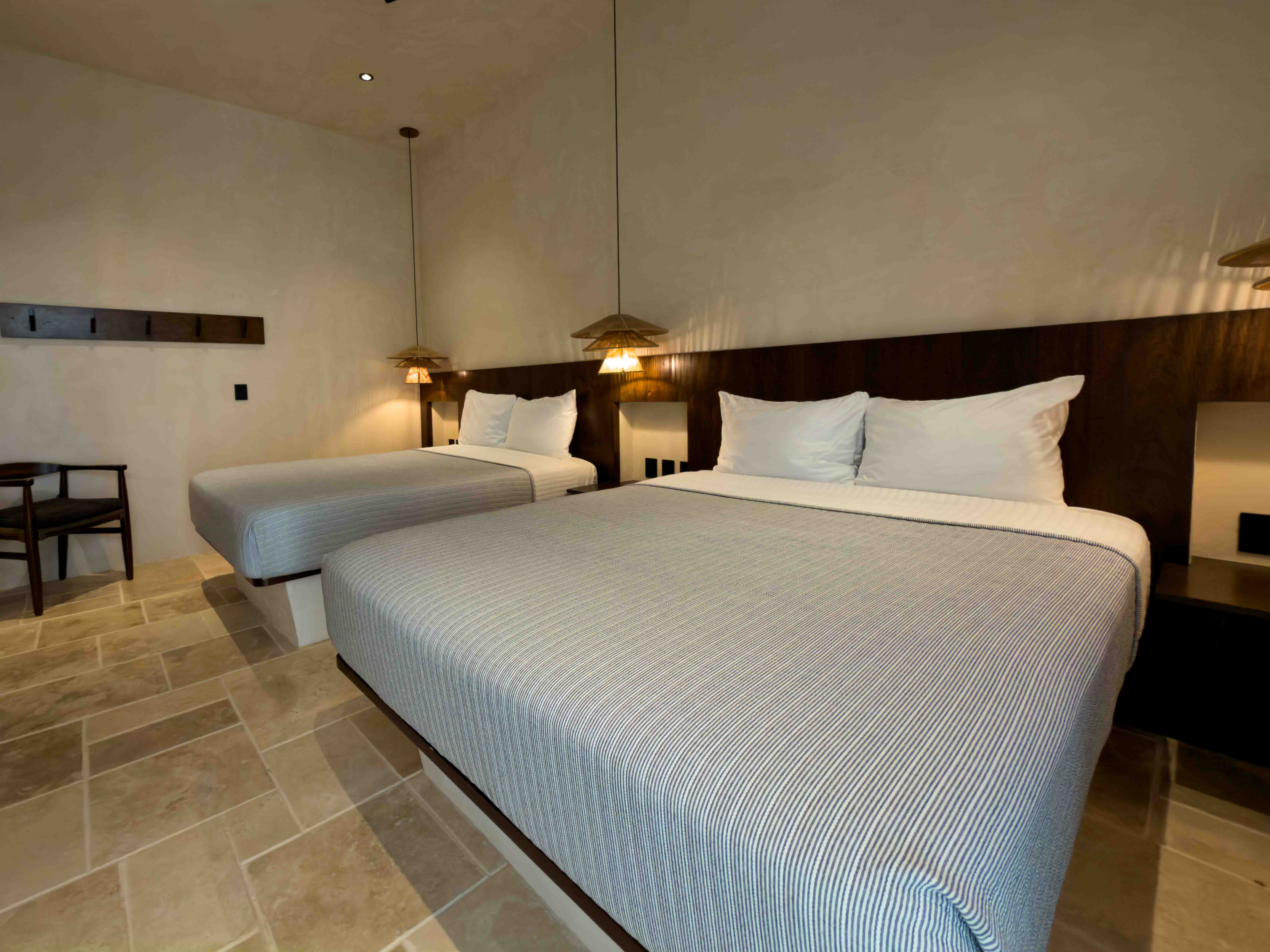 Minimalist double bedroom with stone tile flooring and warm pendant lighting.