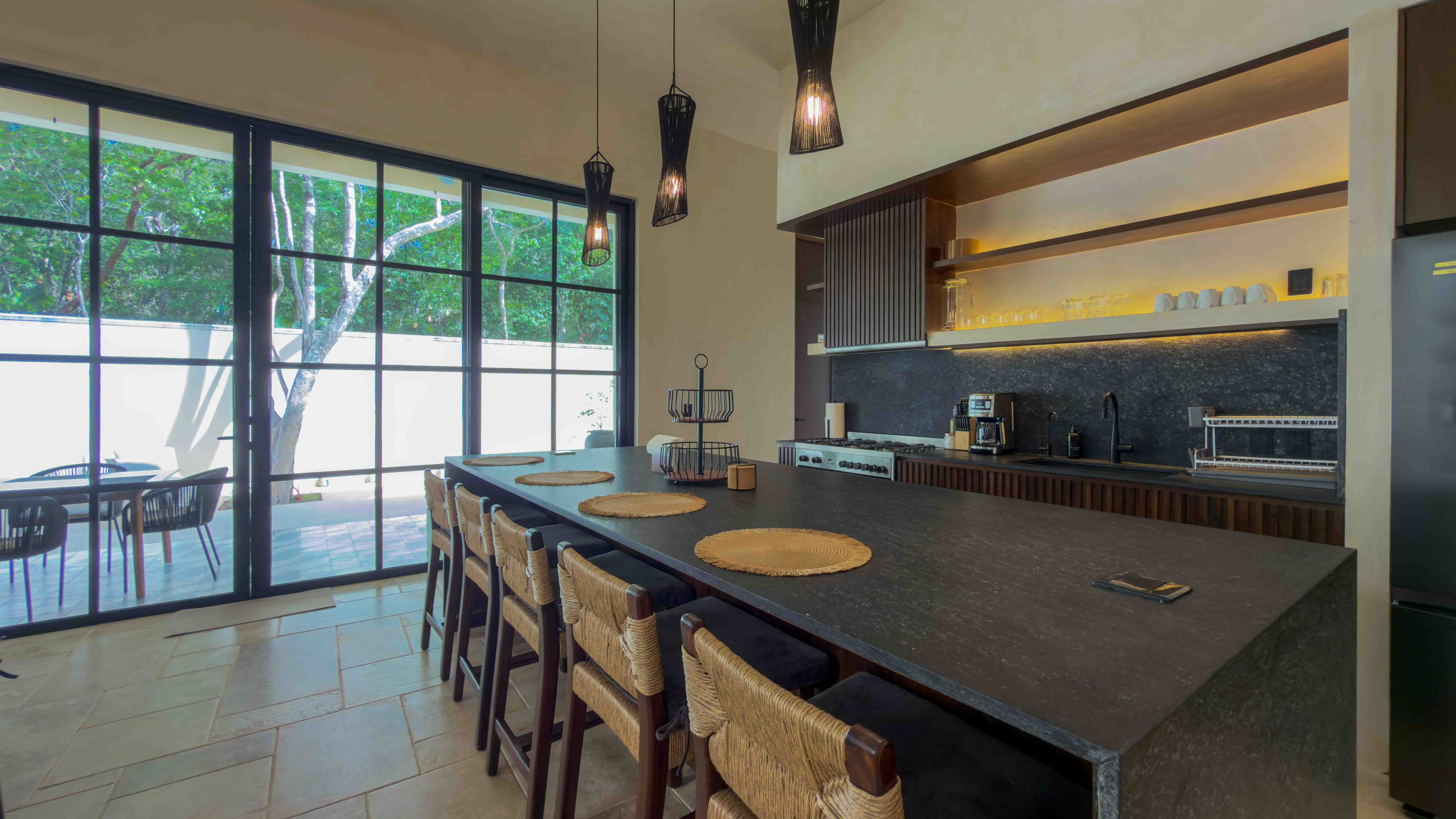 Modern designer kitchen with black stone island and pendant lighting.