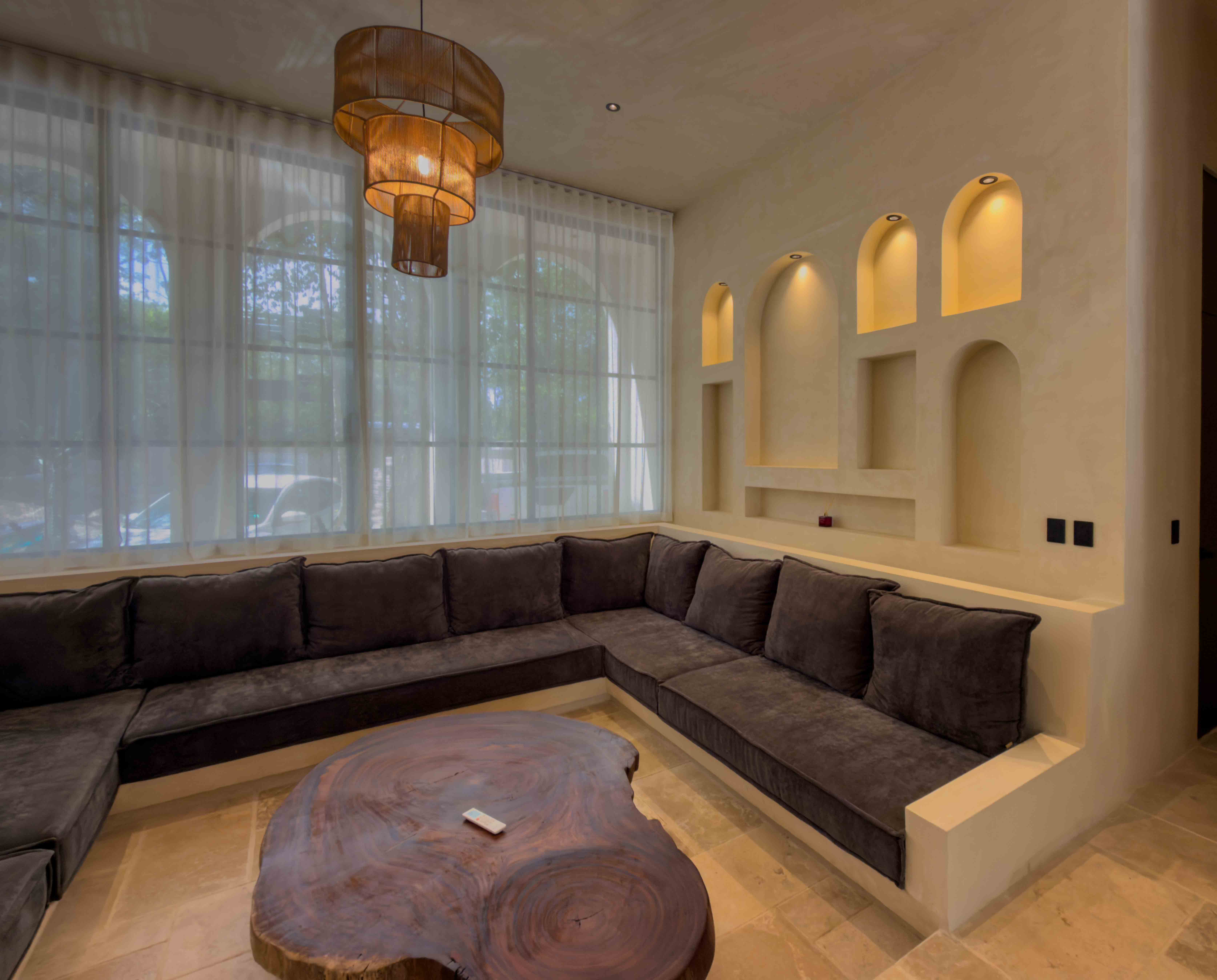 Indoor lounge with built-in seating, live-edge wood table, and arched architectural wall niches.