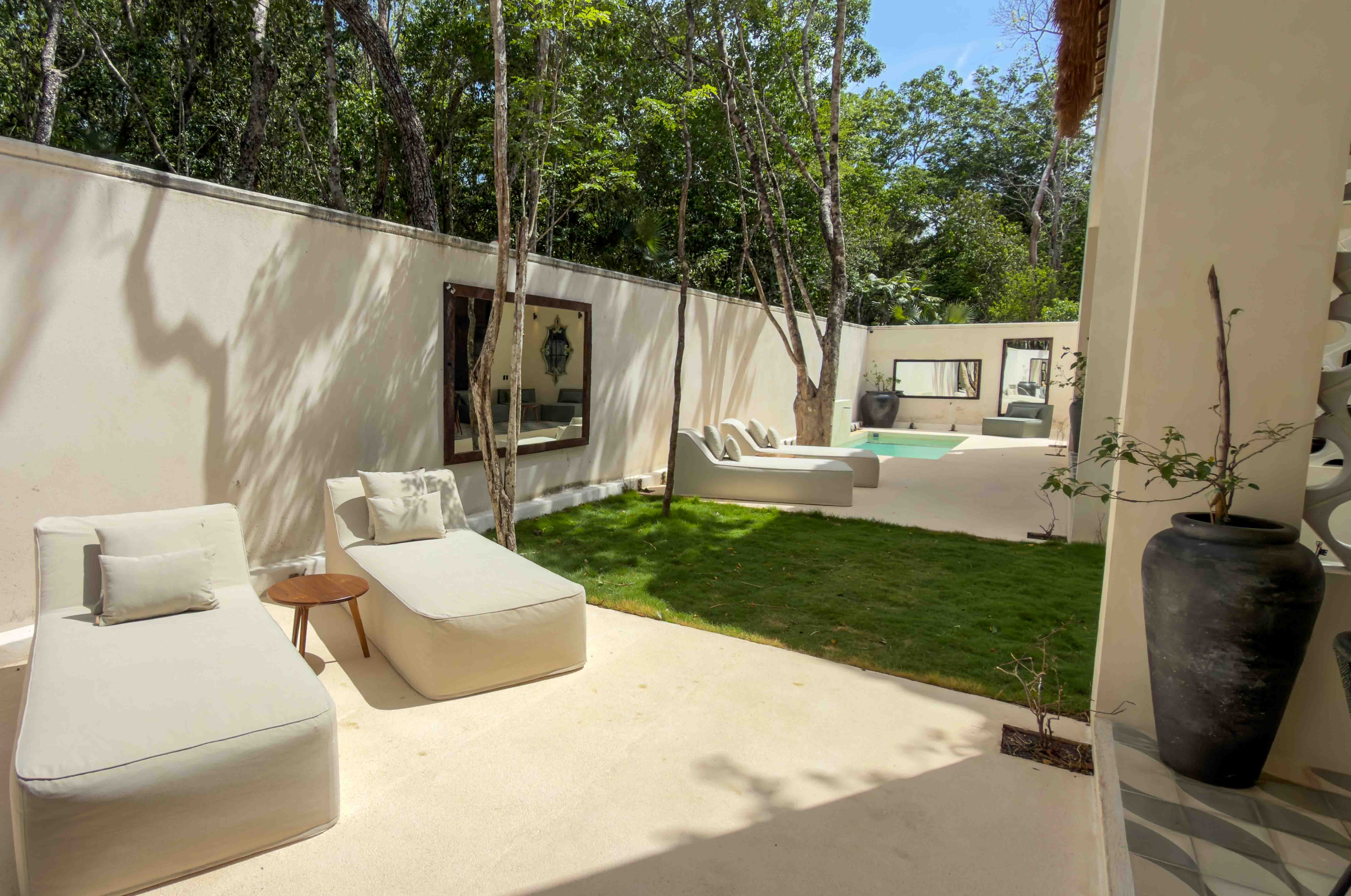 Sun-drenched courtyard with lounge chairs, manicured lawn, and high privacy walls.