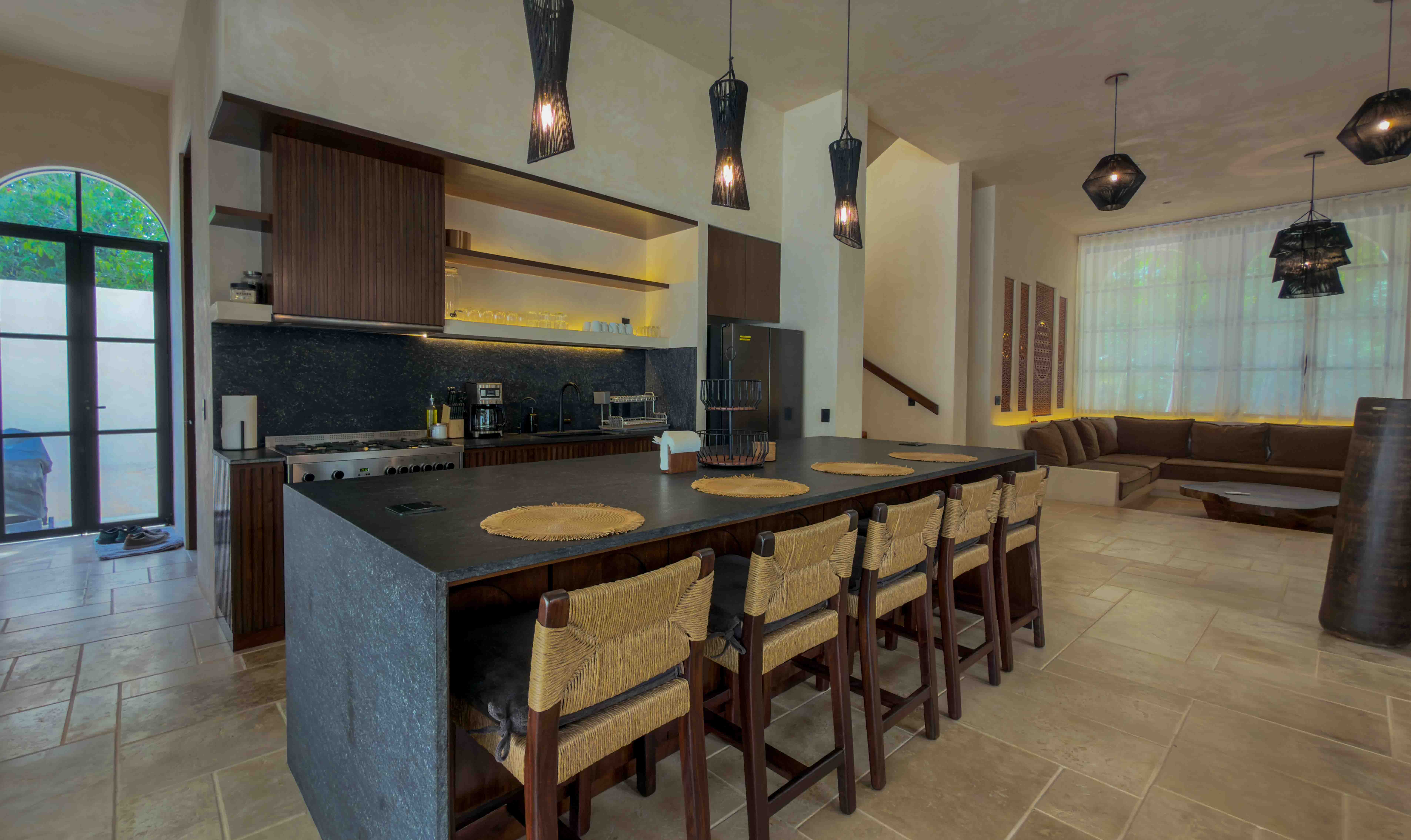 Spacious open plan kitchen and living area with island seating and designer lighting.