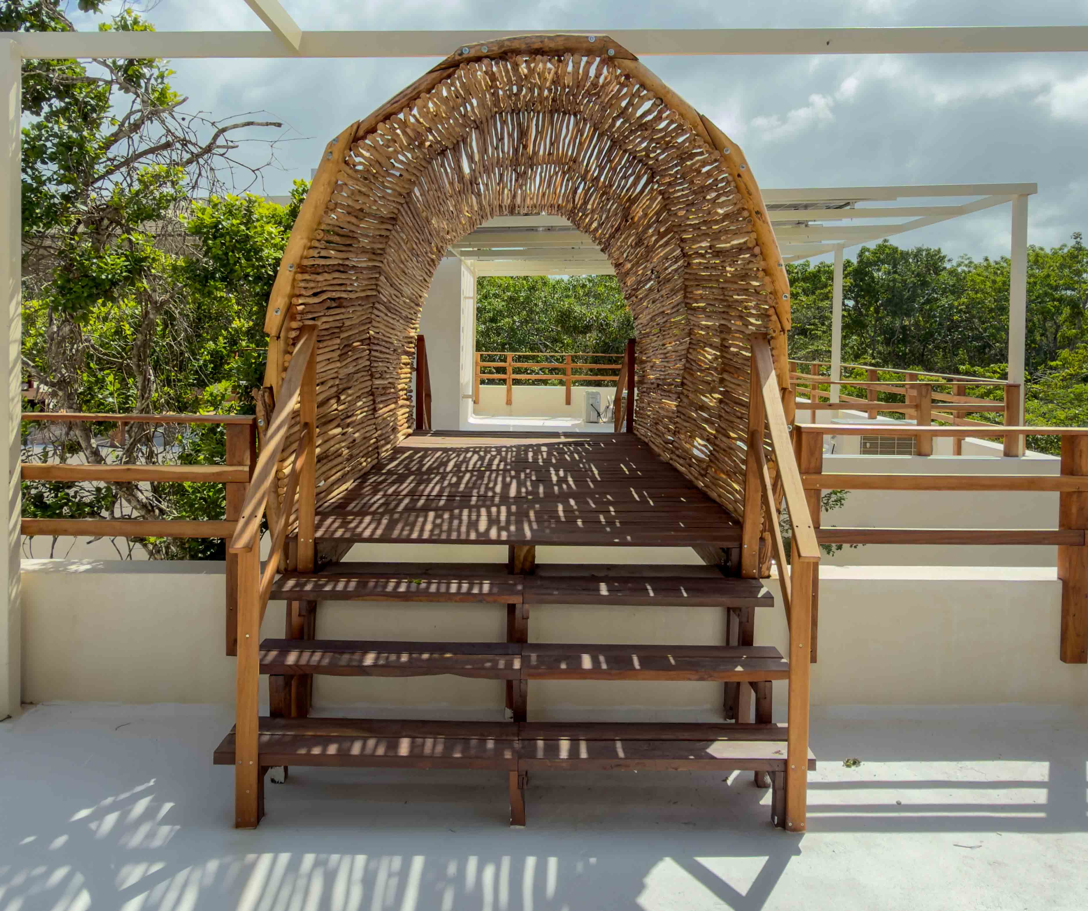Thatched-roof bridge structure on a rooftop walkway with jungle views