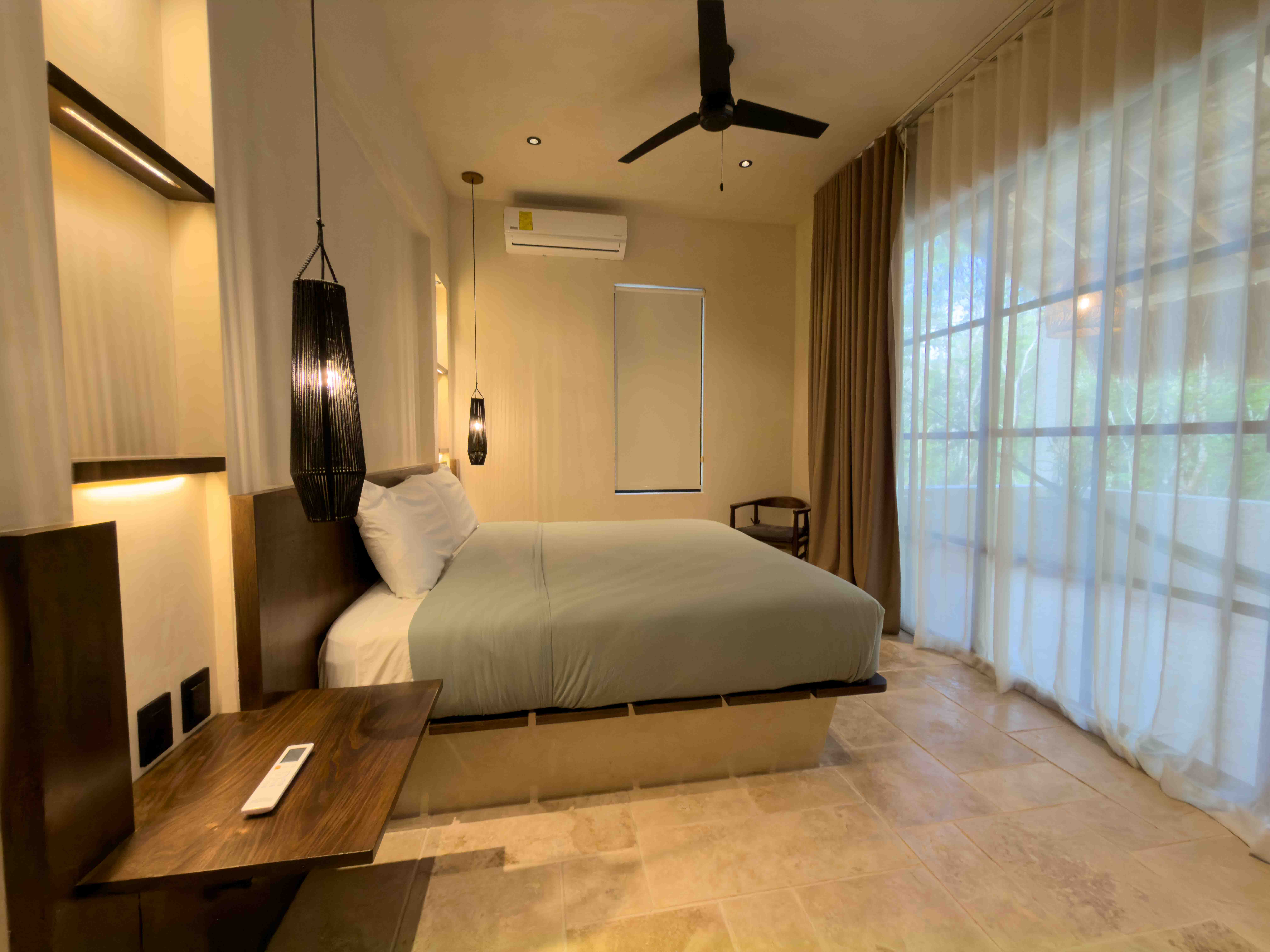 Minimalist luxury bedroom with warm pendant lighting and large glass sliding doors.
