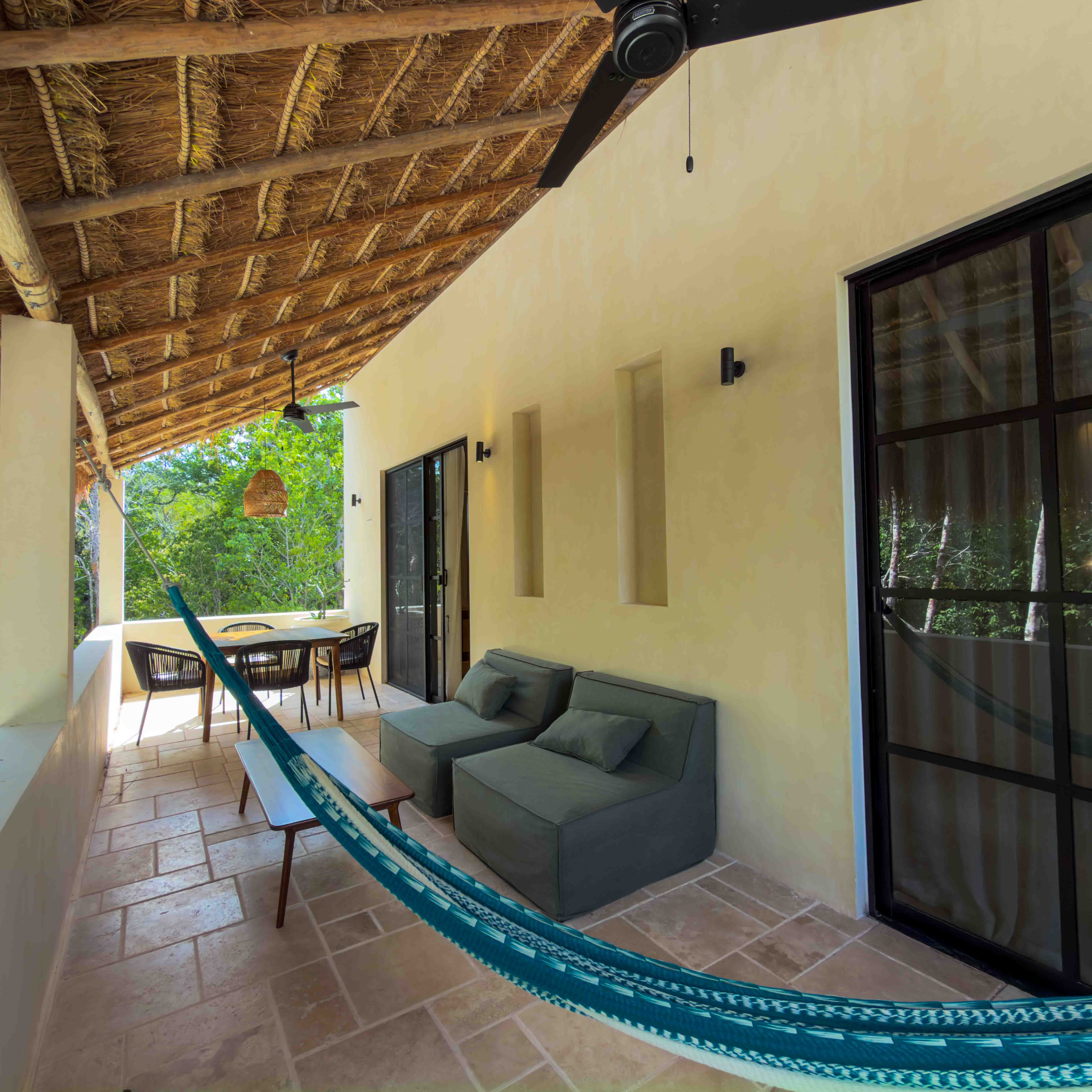 Covered balcony terrace with palapa roof, lounge chairs, and a hammock.